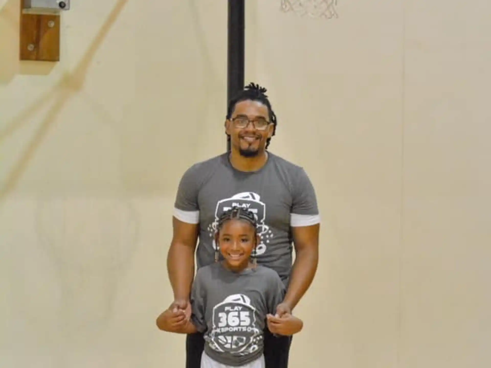 a person and a boy posing for a picture in front of a basketball hoop