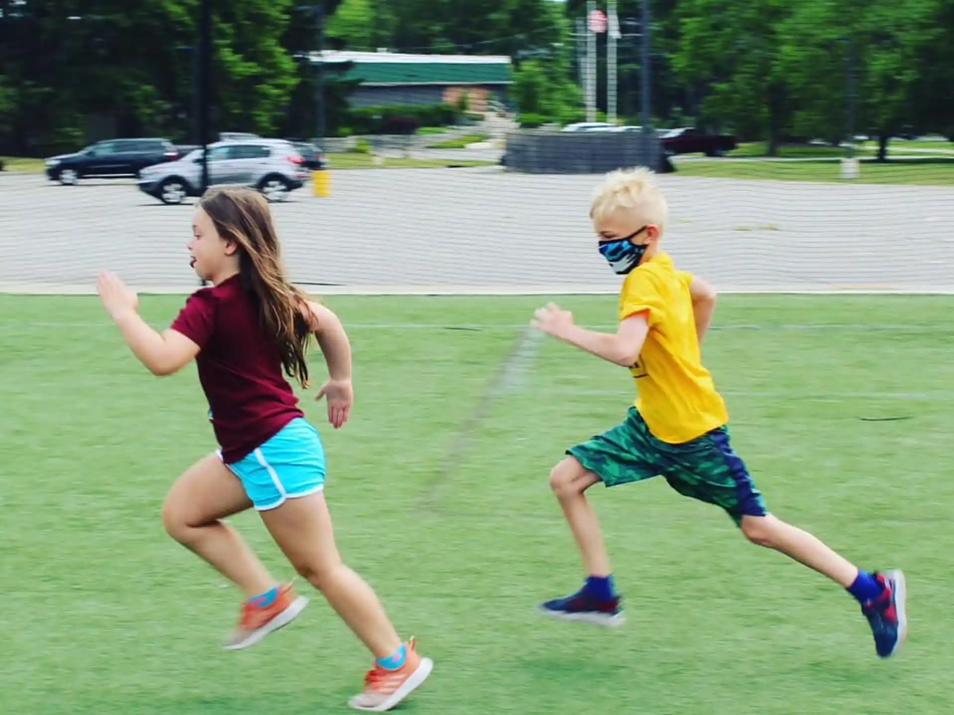 a boy and girl running on a grass field