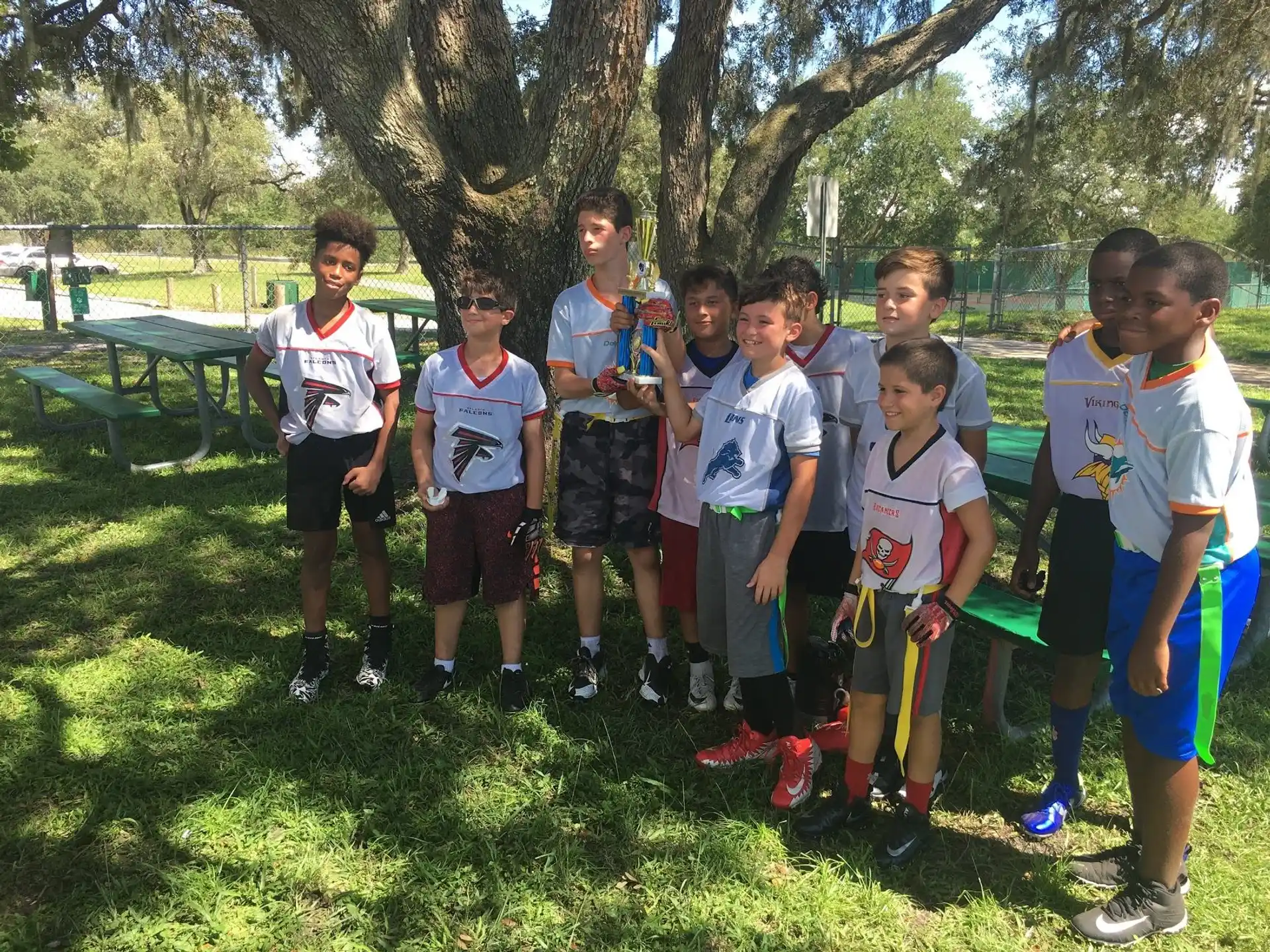 a group of boys in matching t-shirts standing in a grassy area