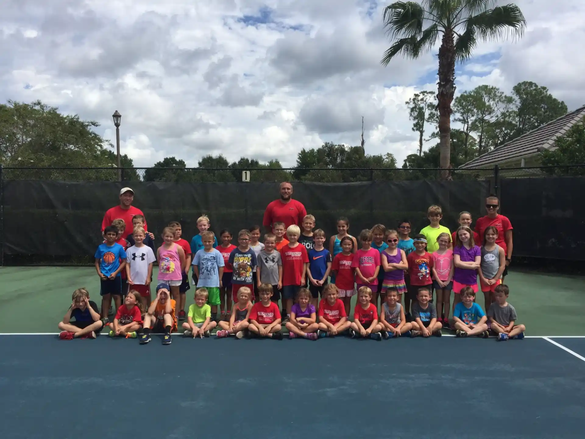 a group of people posing for a photo on a tennis court