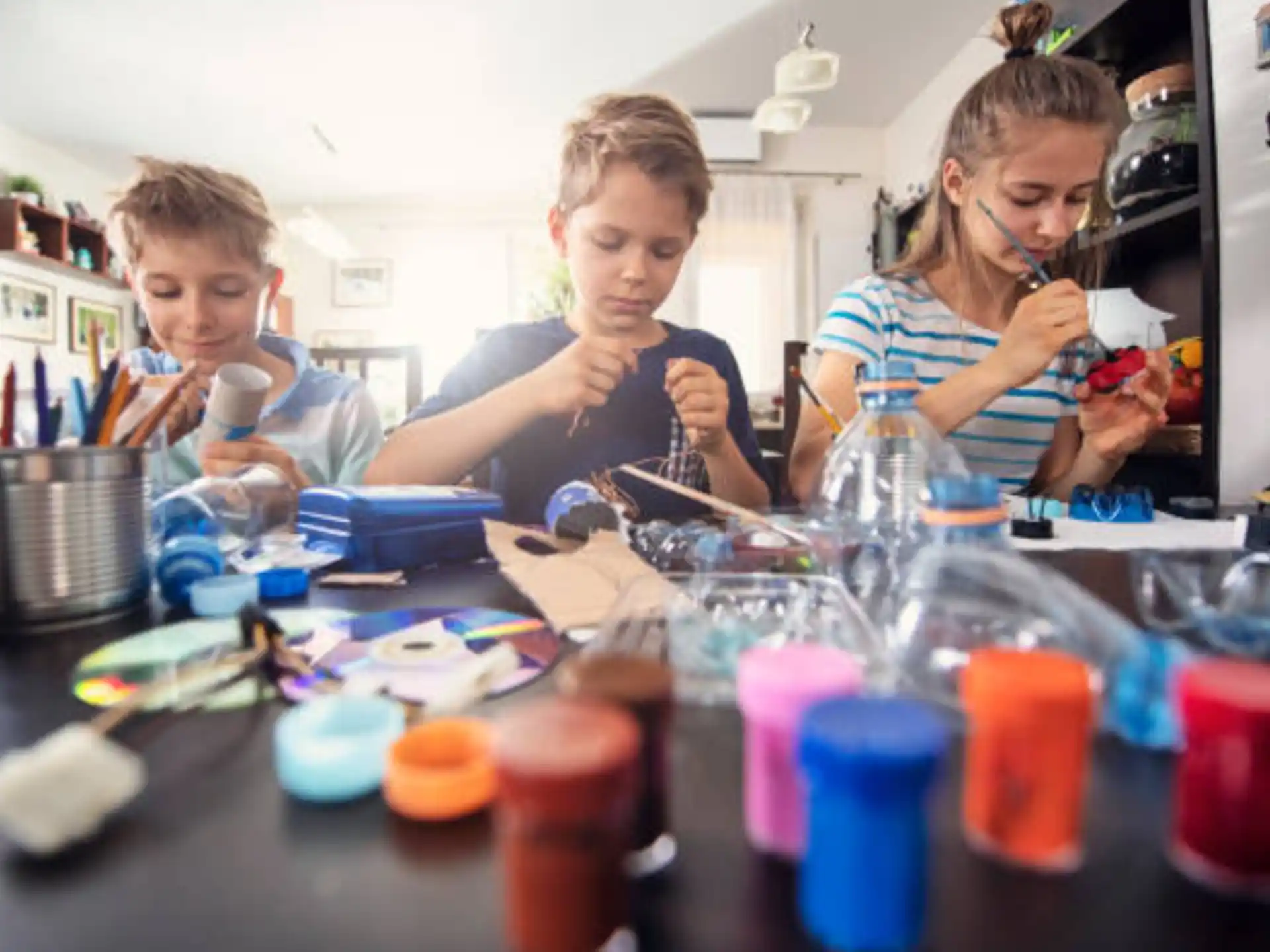 a group of kids sitting at a table with colored pencils