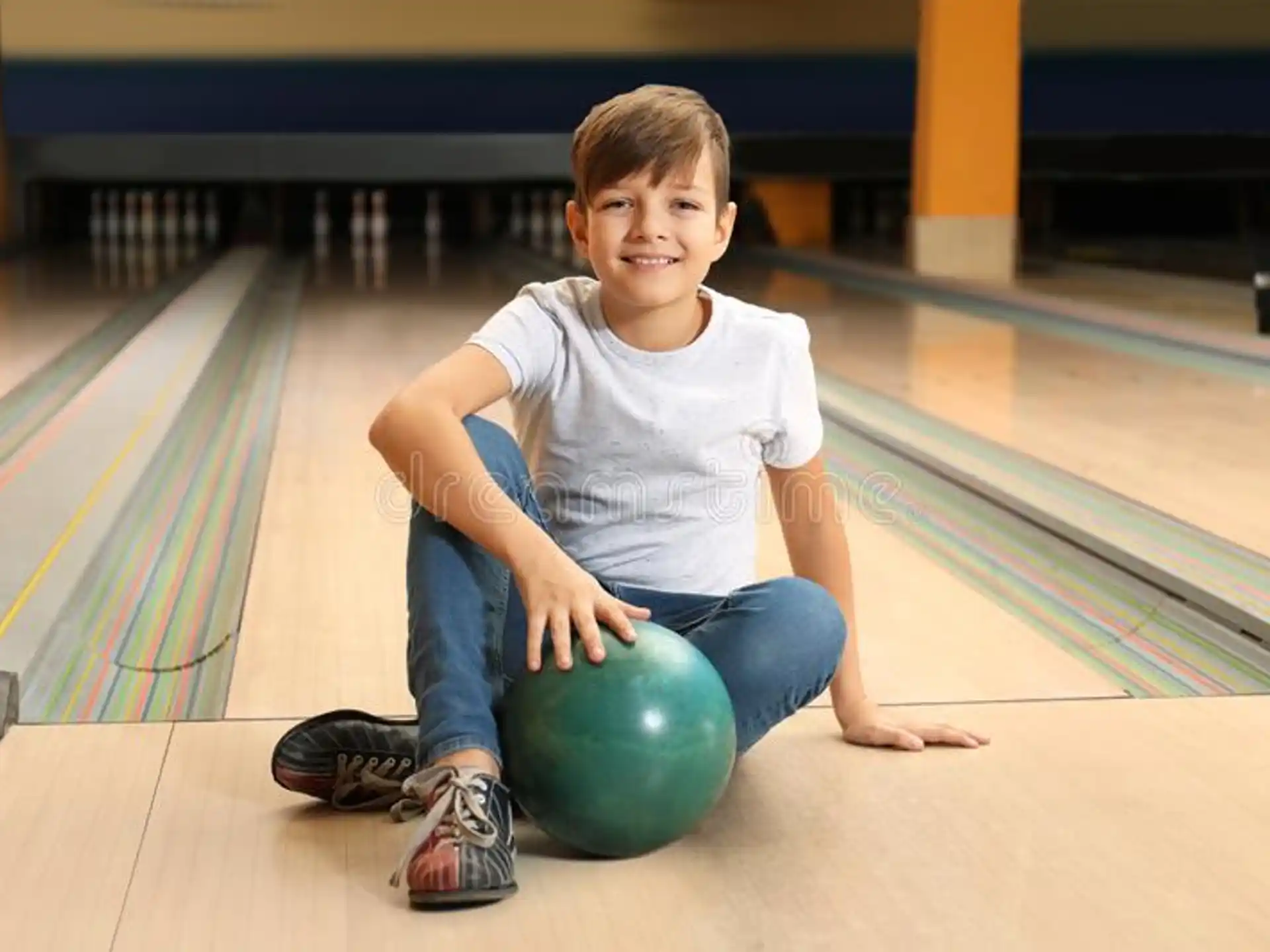 a boy sitting on a bowling ball