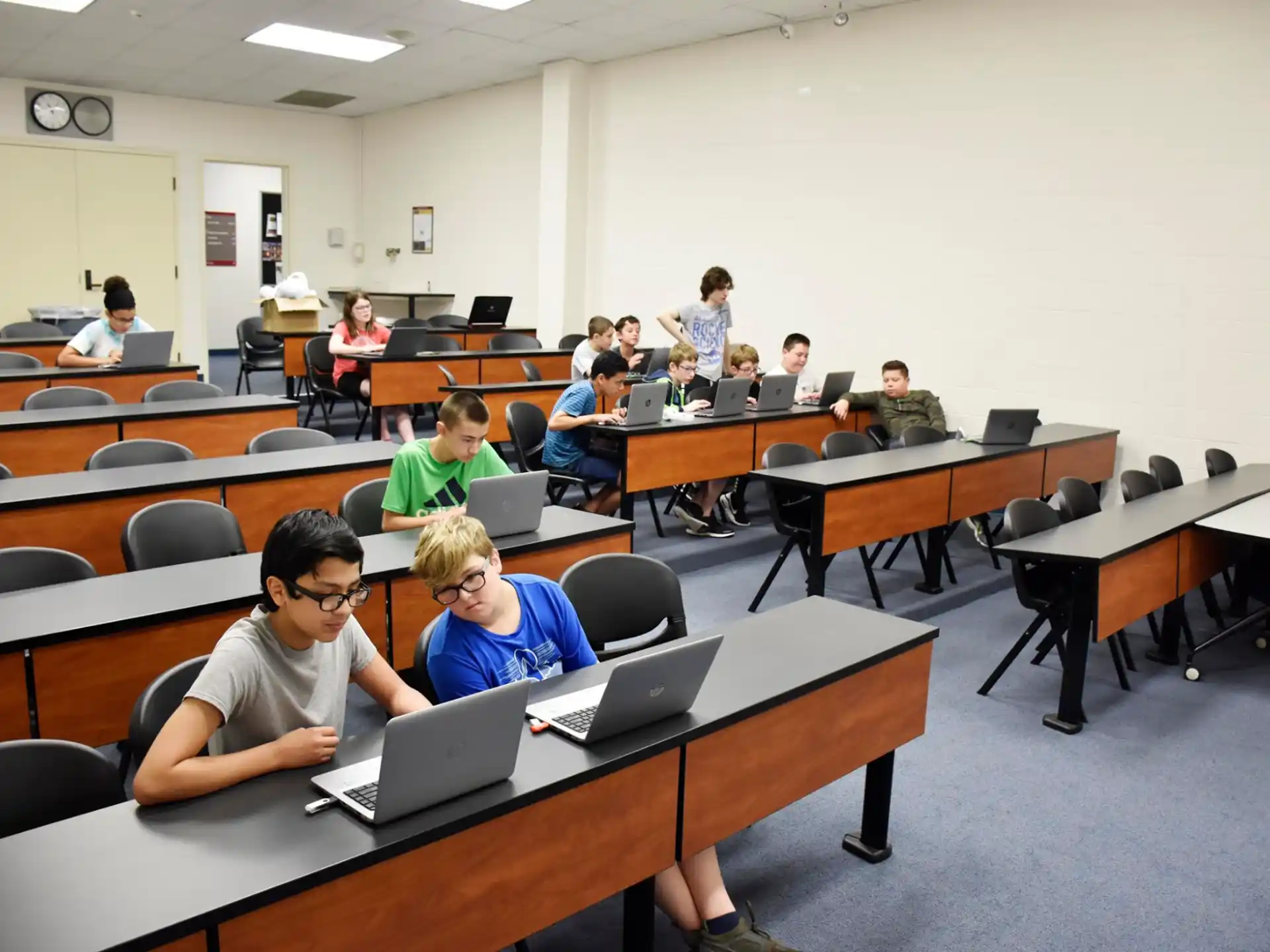 a group of people sitting at desks with laptops