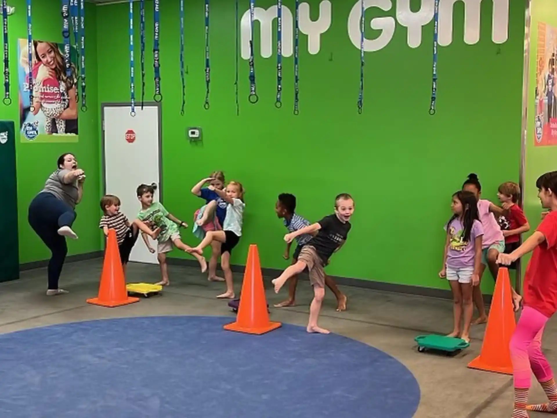 a group of kids playing on a mat in front of a green wall