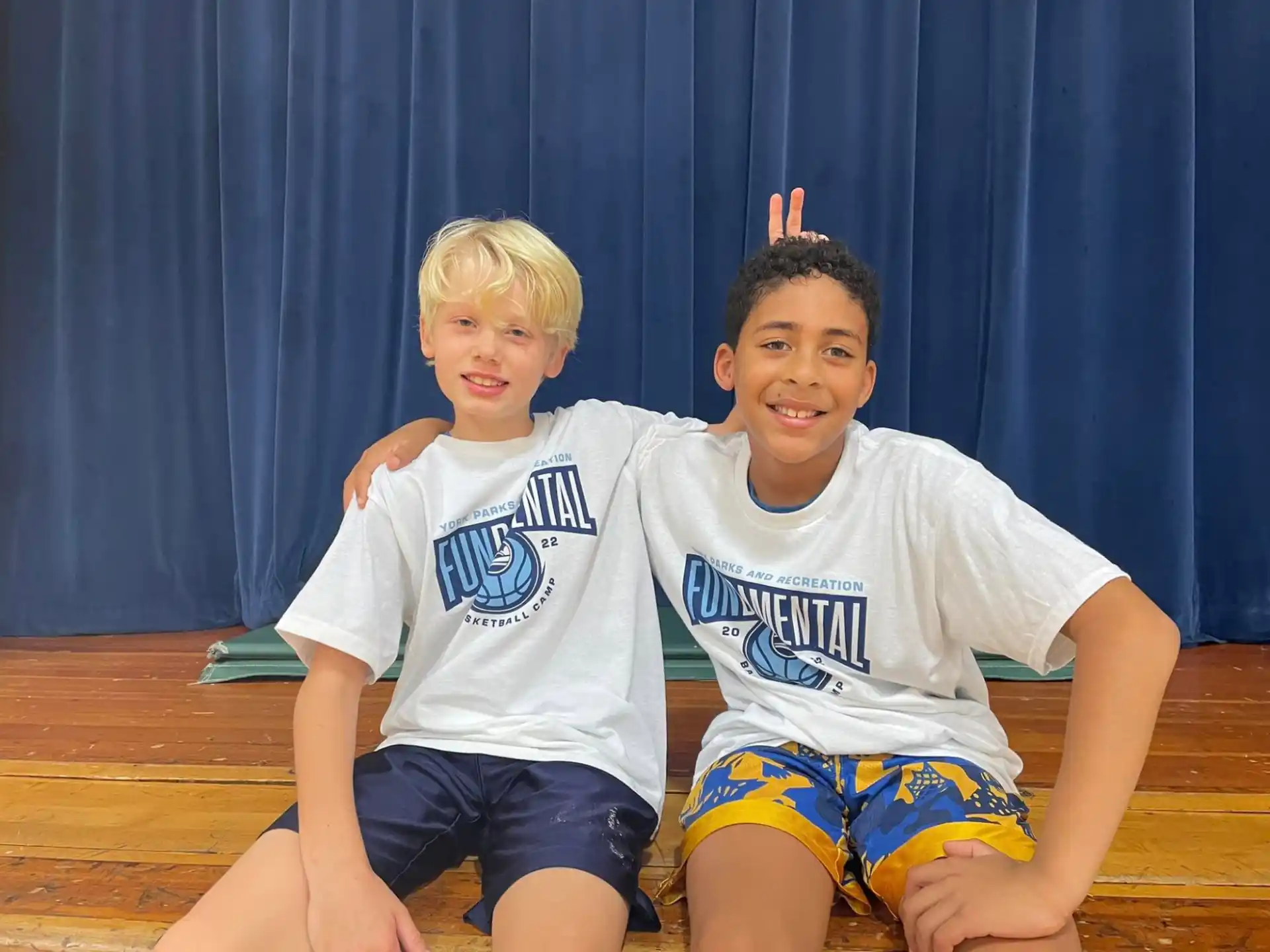 two boys sitting on a wood floor