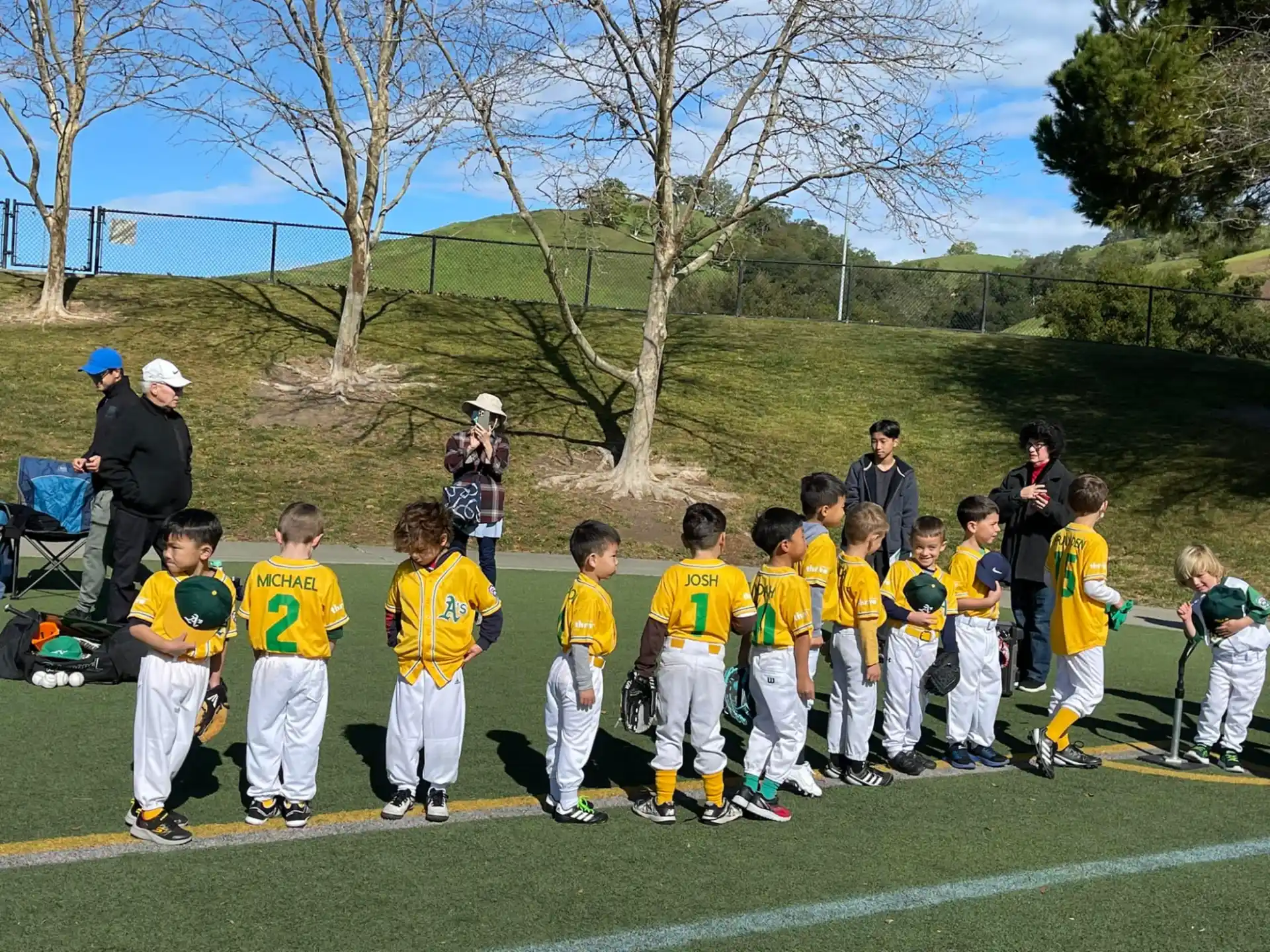 a group of kids in yellow uniforms standing on a field