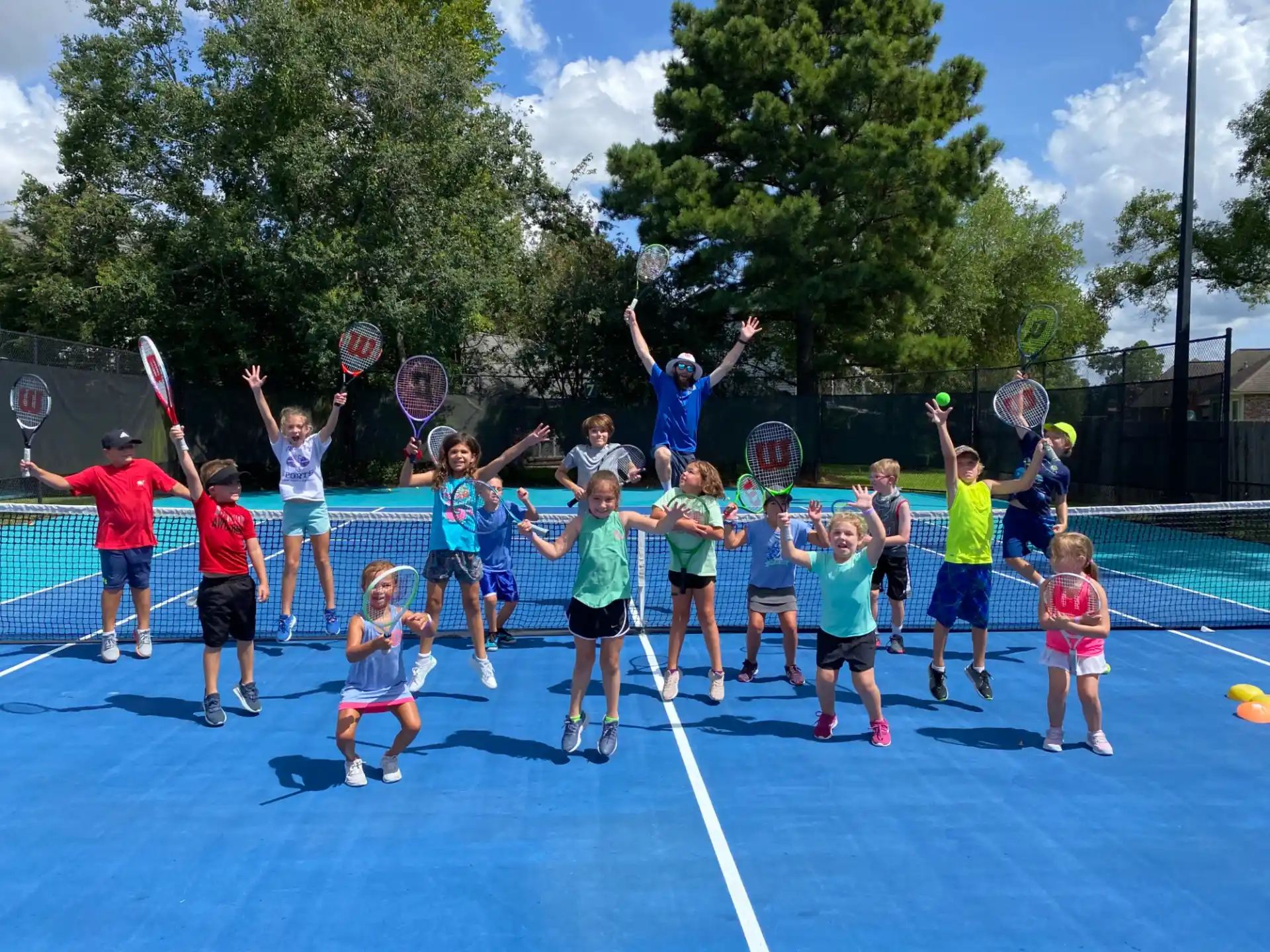 a group of kids holding tennis rackets on a court