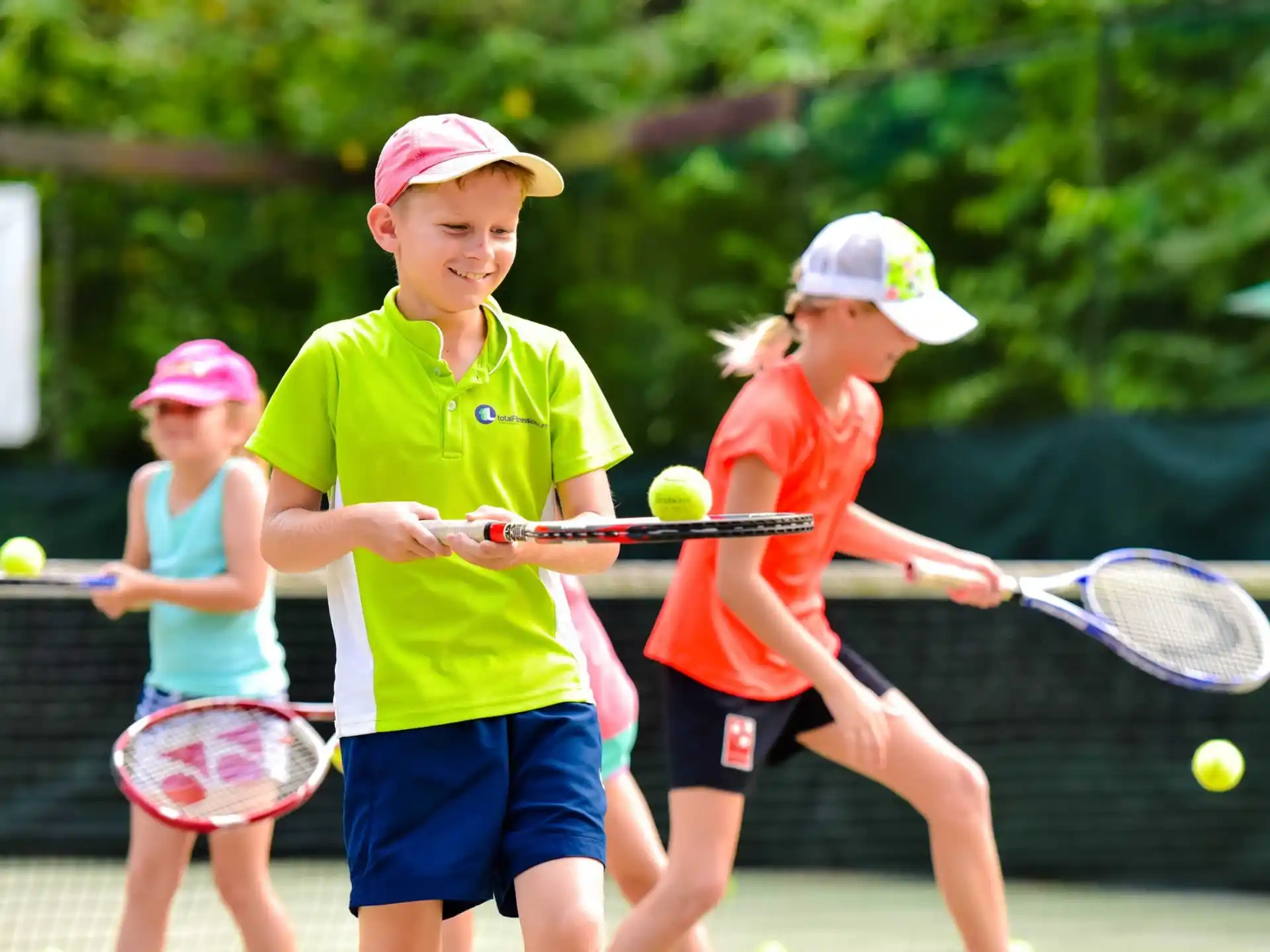 a group of kids playing tennis