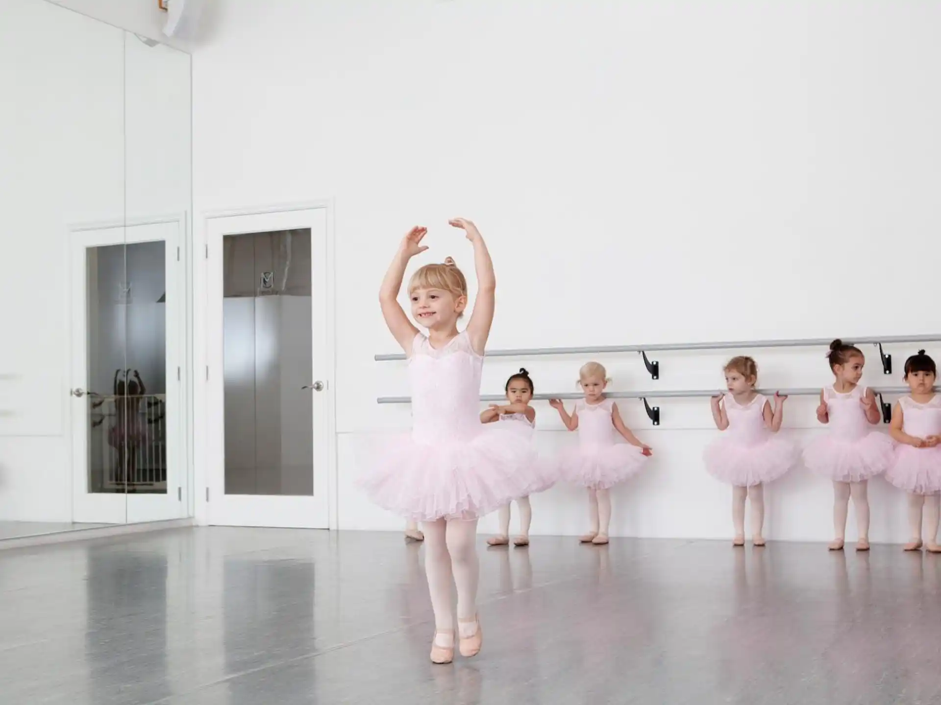a group of girls in white dresses dancing on a stage