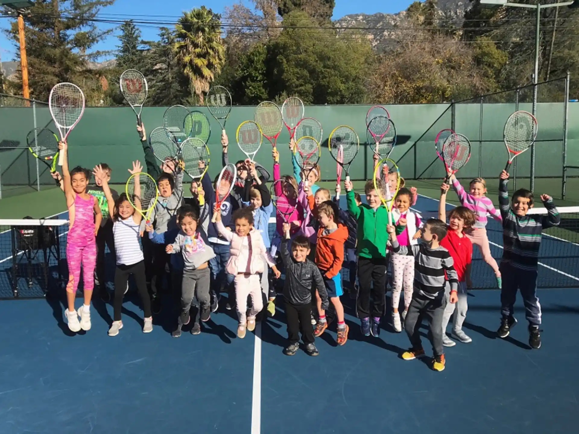 a group of kids holding tennis rackets