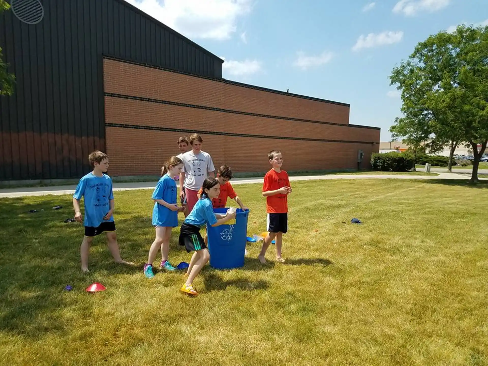 a group of kids playing with a blue bin