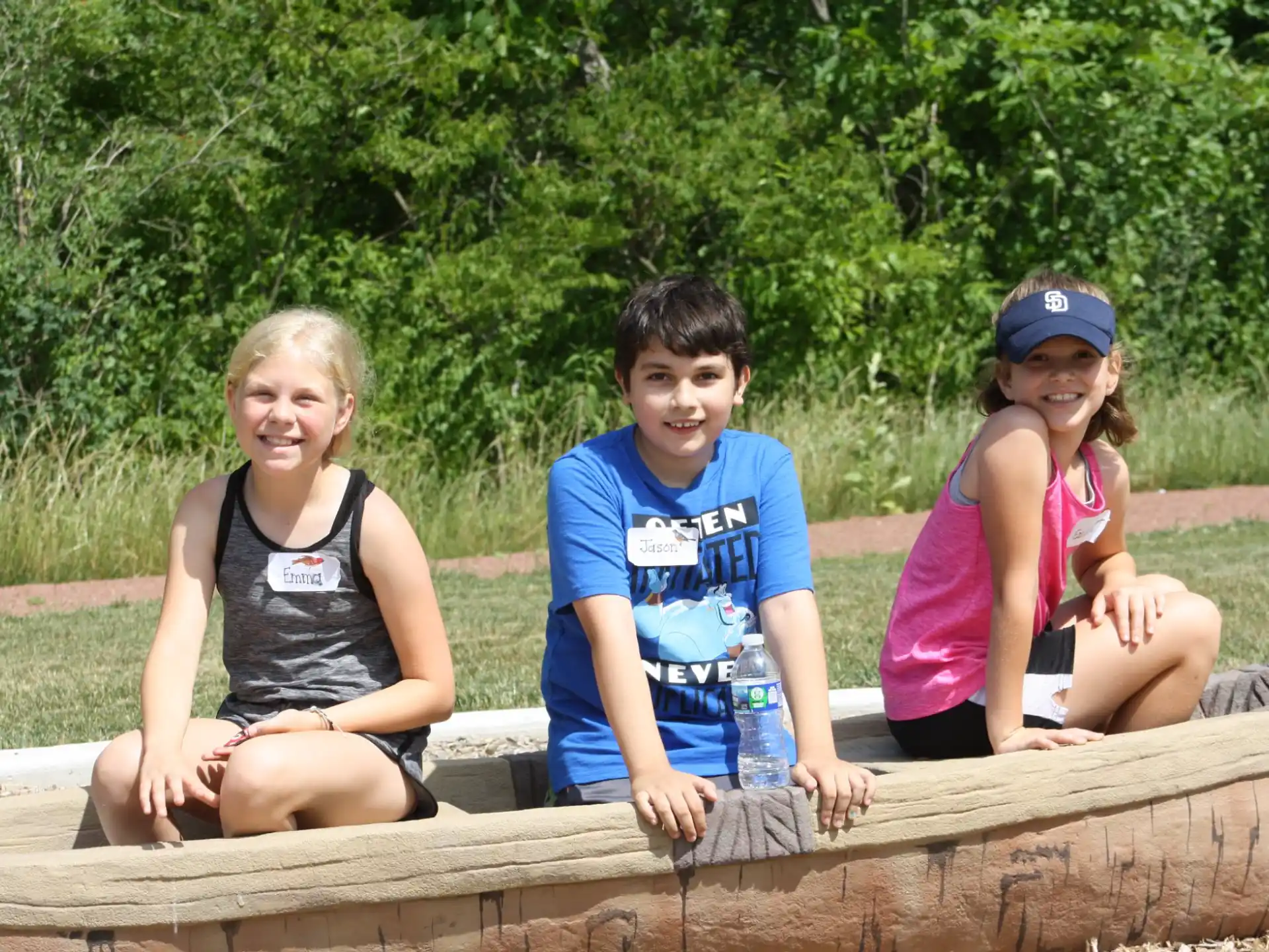 a group of people sitting on a log posing for the camera