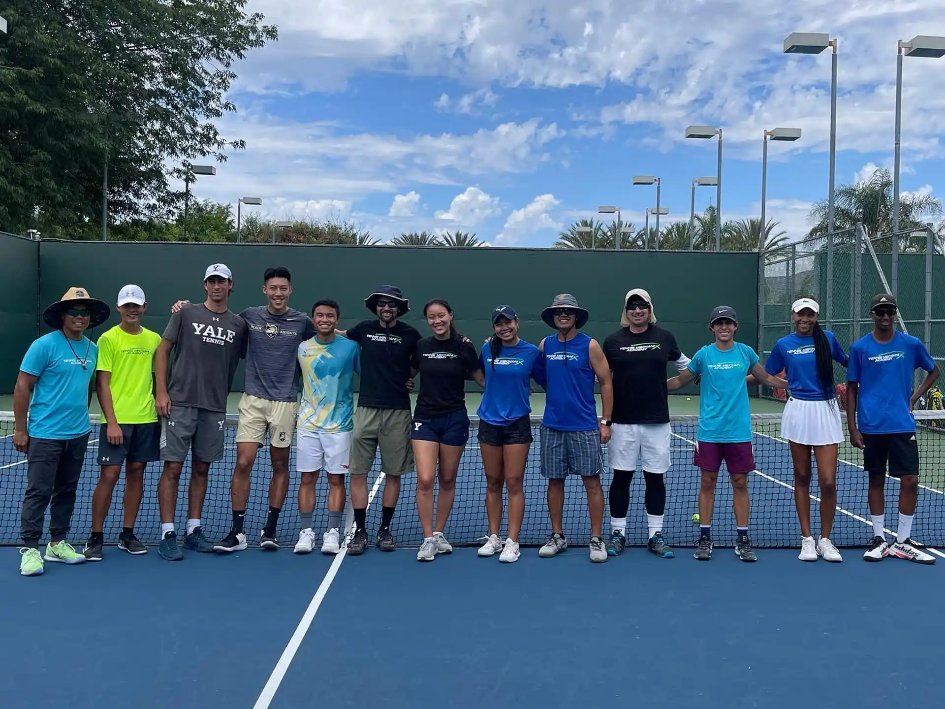 a group of people posing for a photo on a tennis court