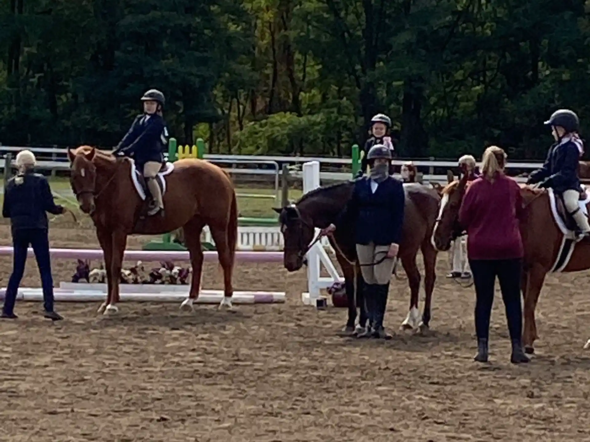 people riding horses in a dirt arena