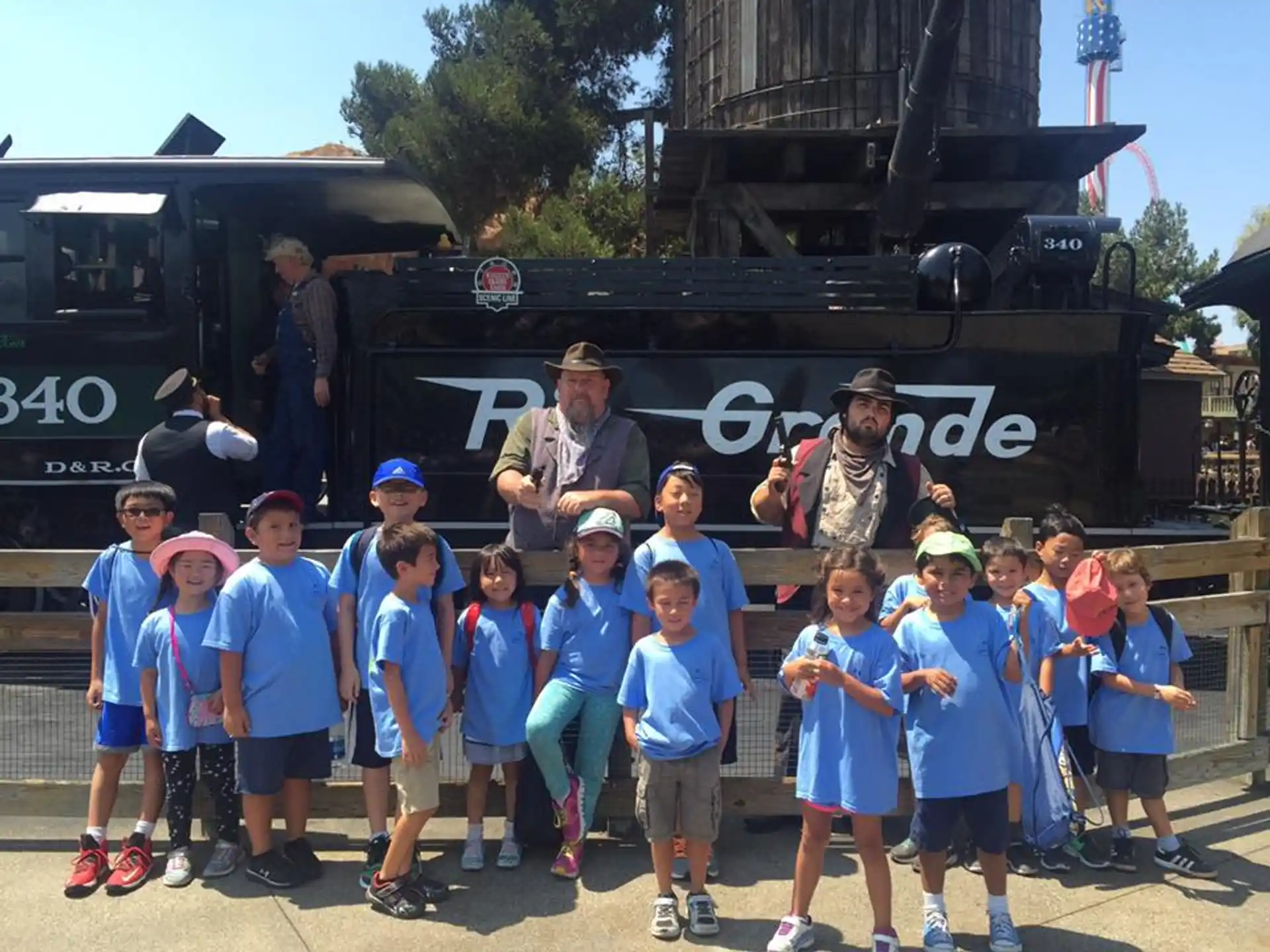 a group of kids posing for a photo in front of a train