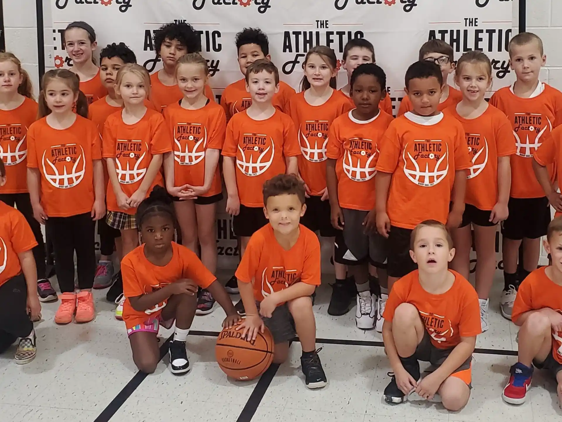 a group of kids wearing orange shirts and holding basketballs