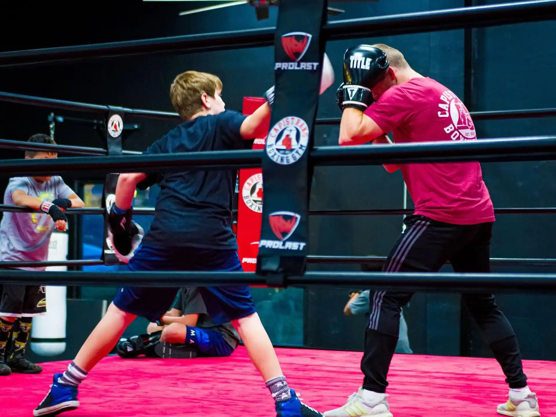 a person in a boxing ring with another man in the back