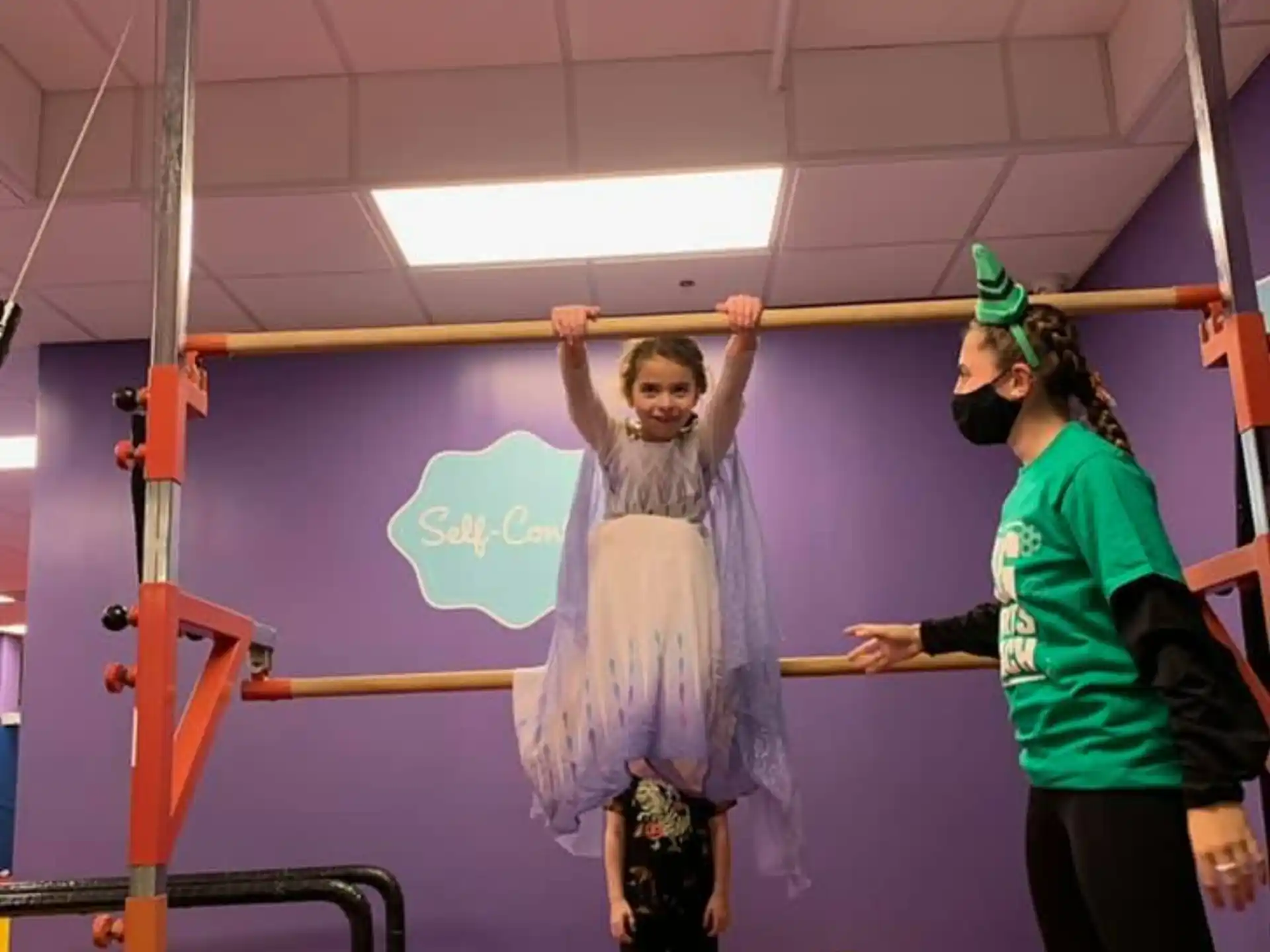 a person holding a child on the head in a room with a red mat and a person in