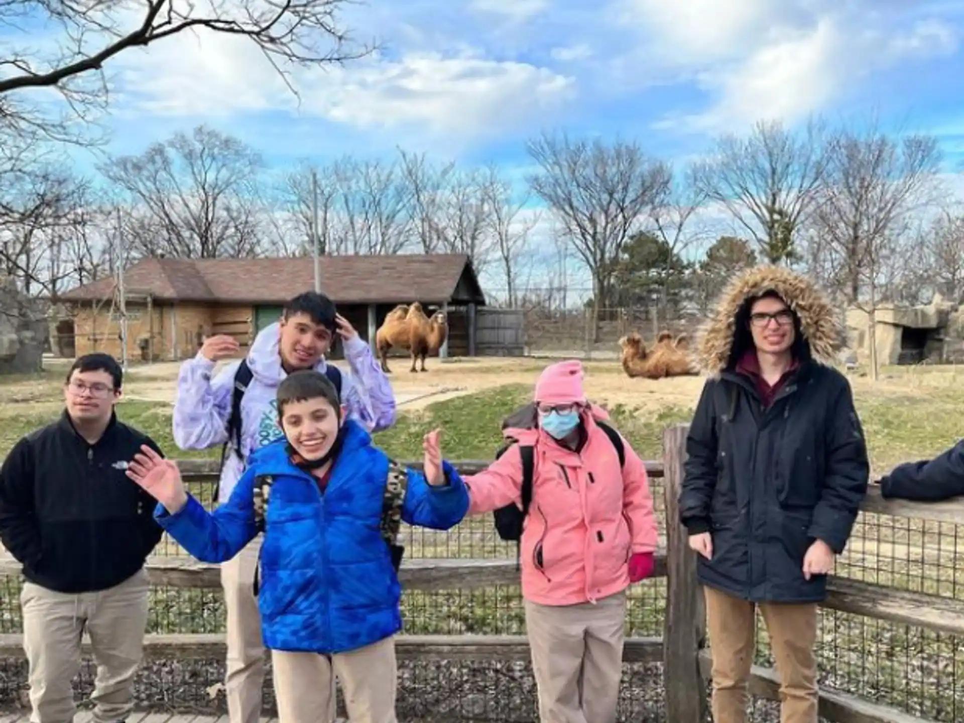 a group of people posing for a photo in front of a fence