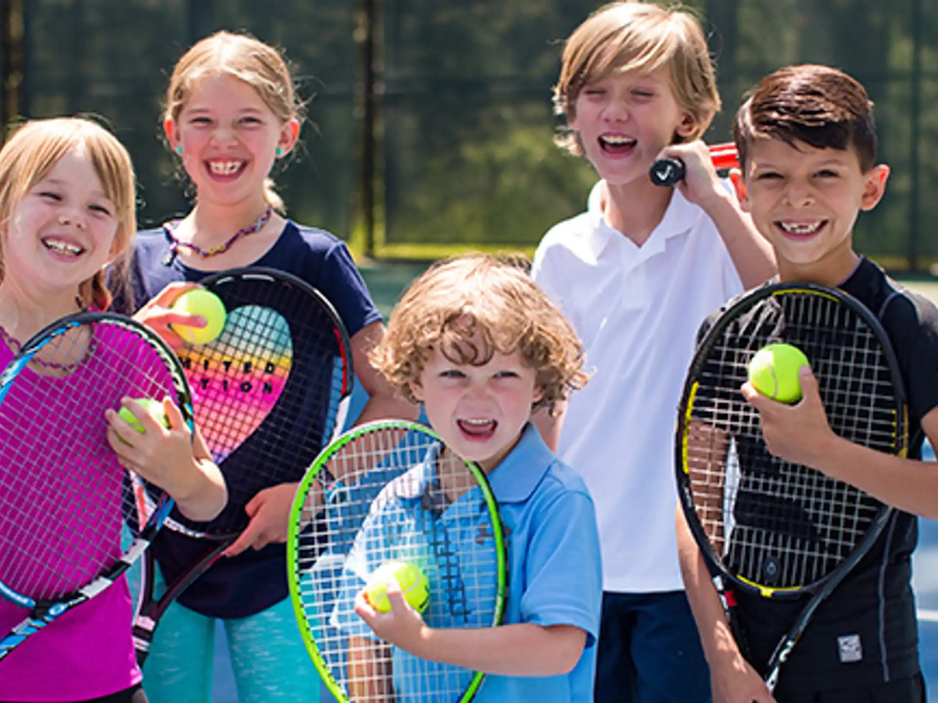 a group of kids holding tennis rackets