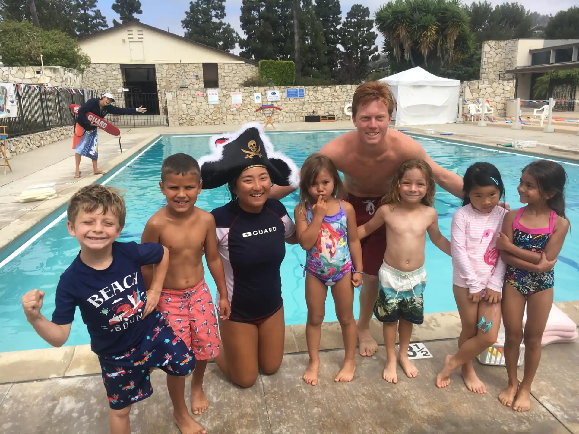a group of children posing for a photo by a pool