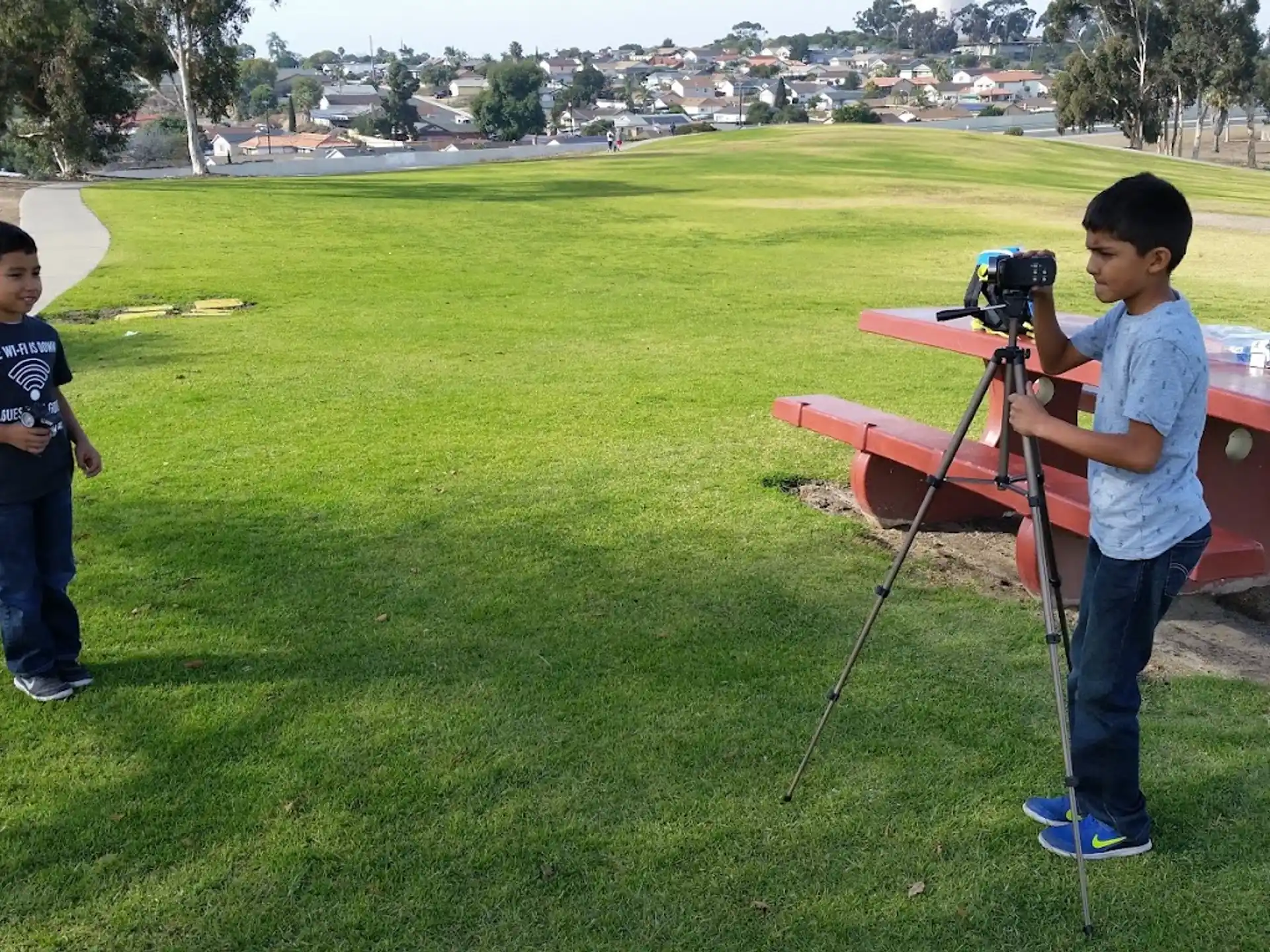 a couple of boys standing next to a table with a camera on it