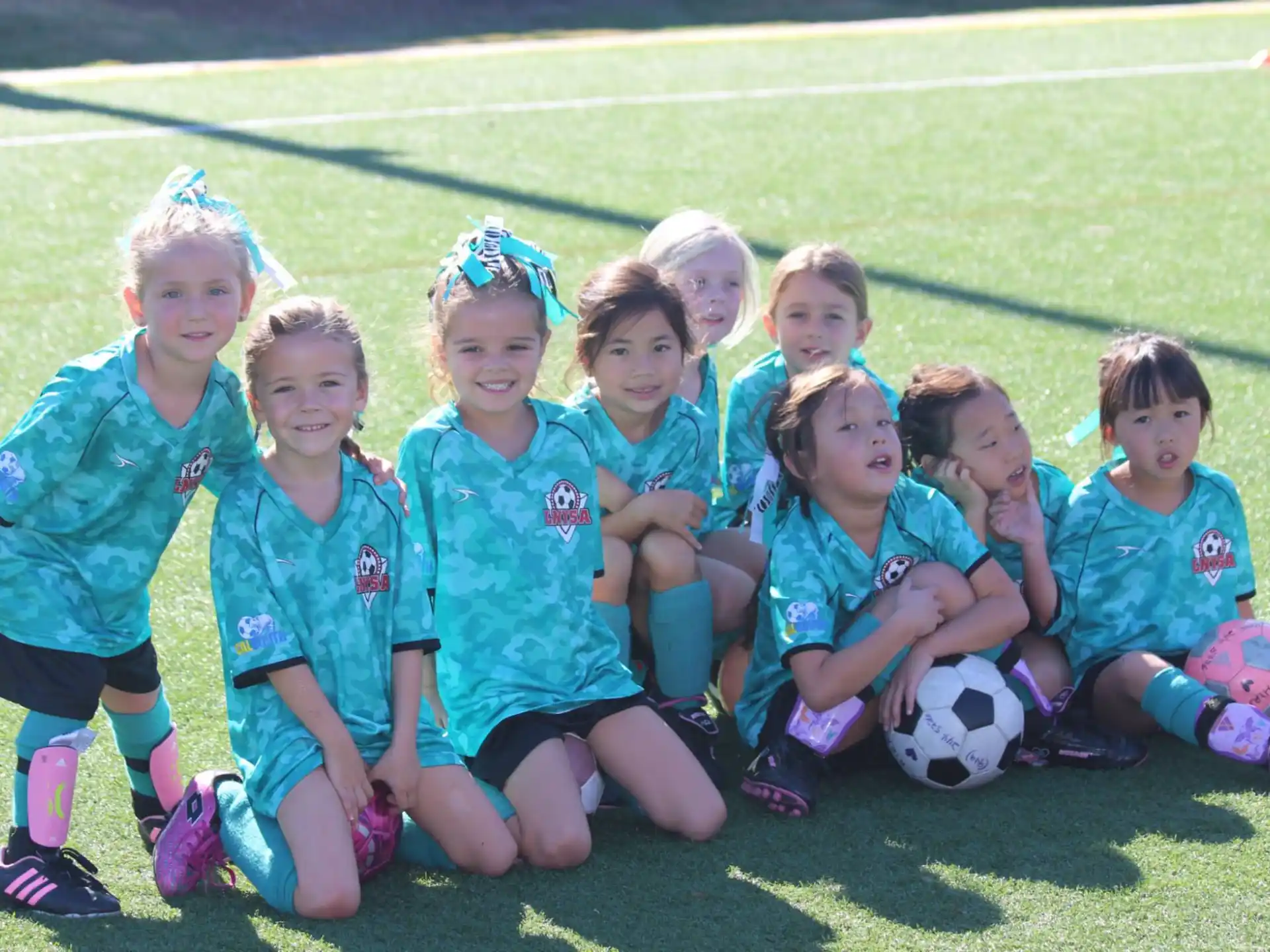 a group of girls posing for a picture with a football ball