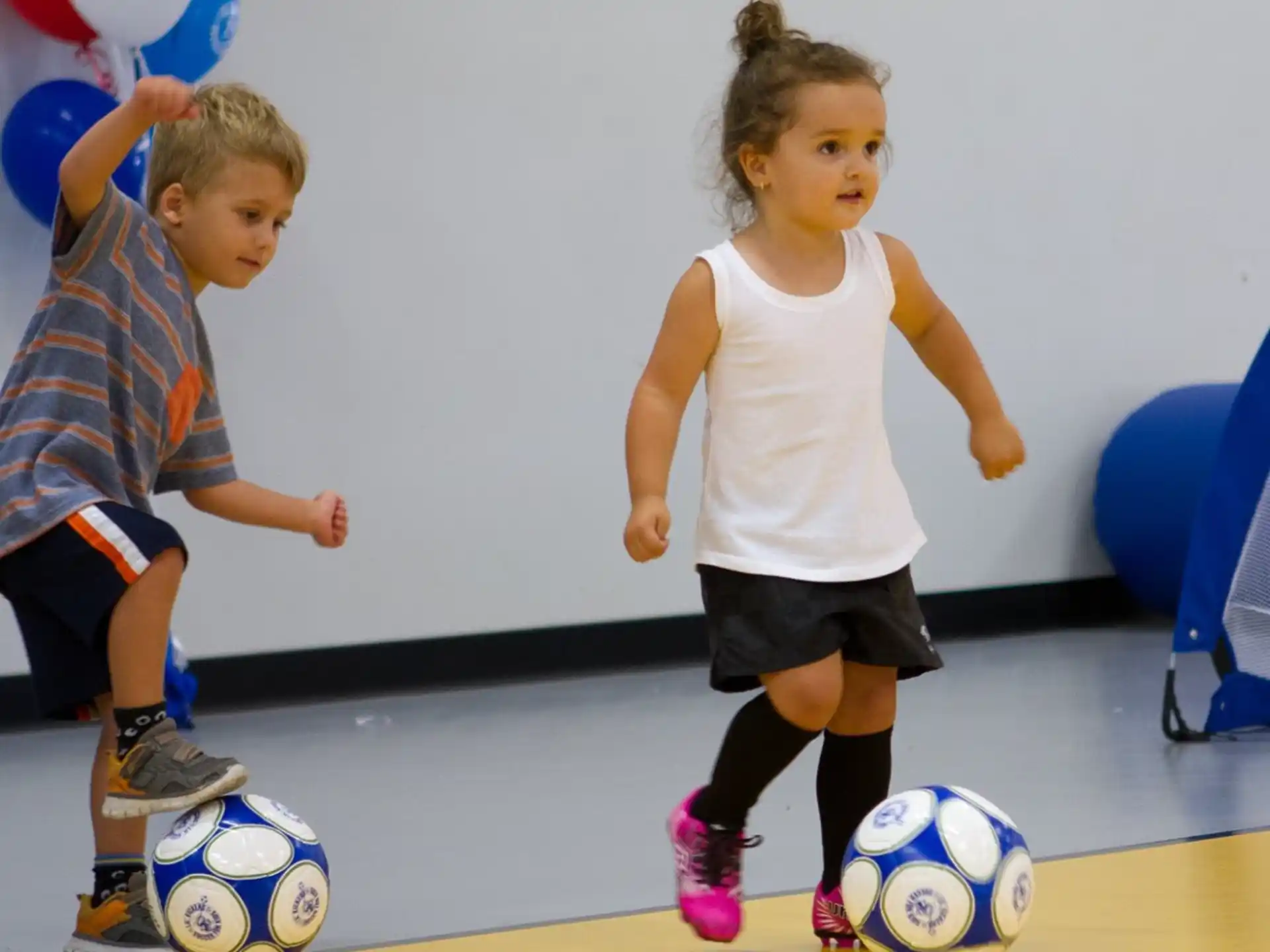 a couple of children playing with a football ball