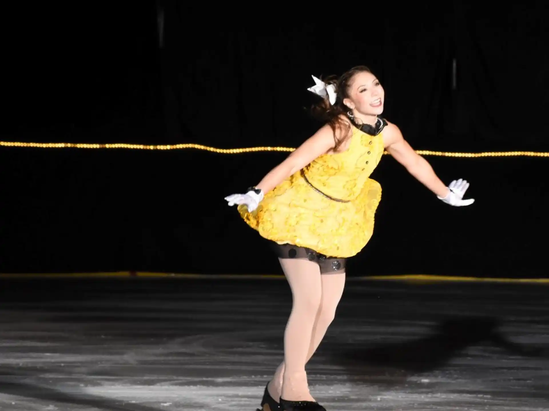 a woman wearing a yellow dress and dancing on ice