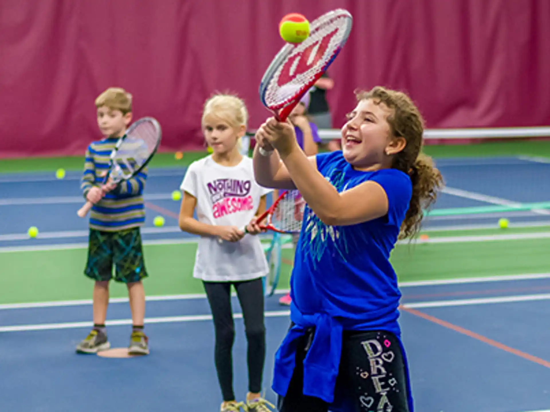 a group of kids playing tennis