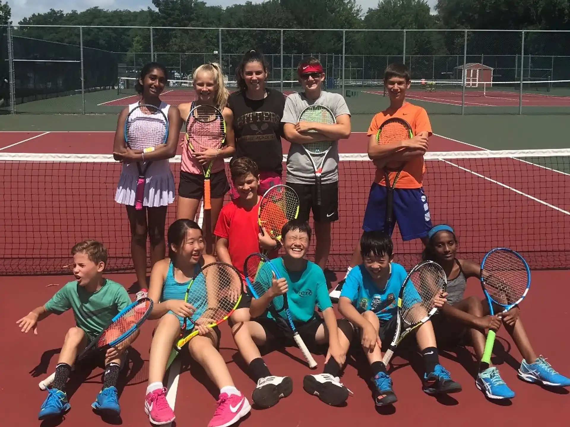 a group of kids posing for a photo with tennis rackets