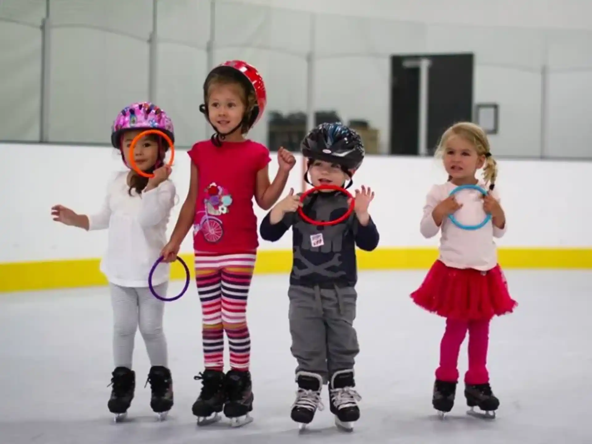 a group of kids wearing ice skates and helmets