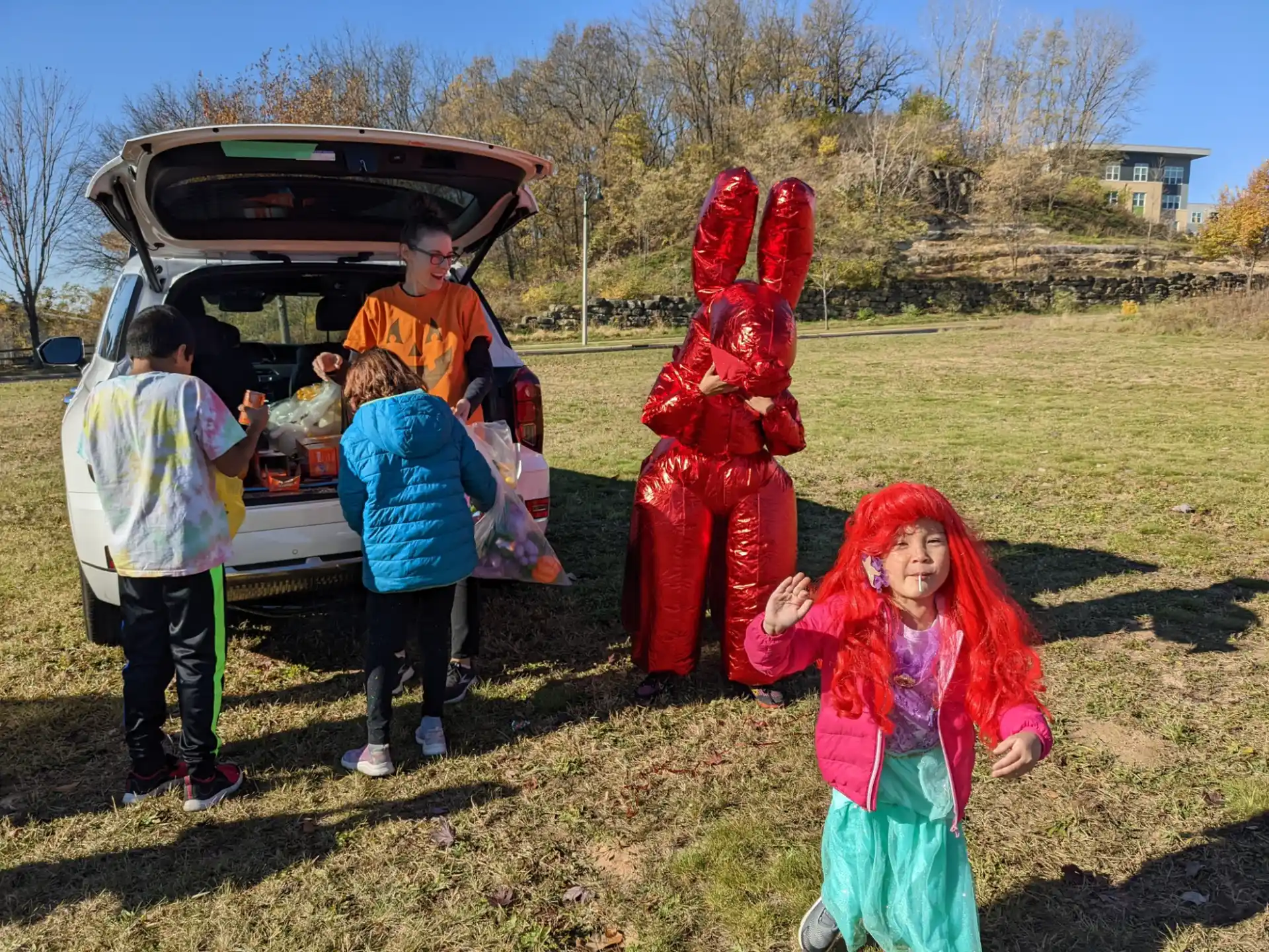 a group of people in clothing standing outside a car
