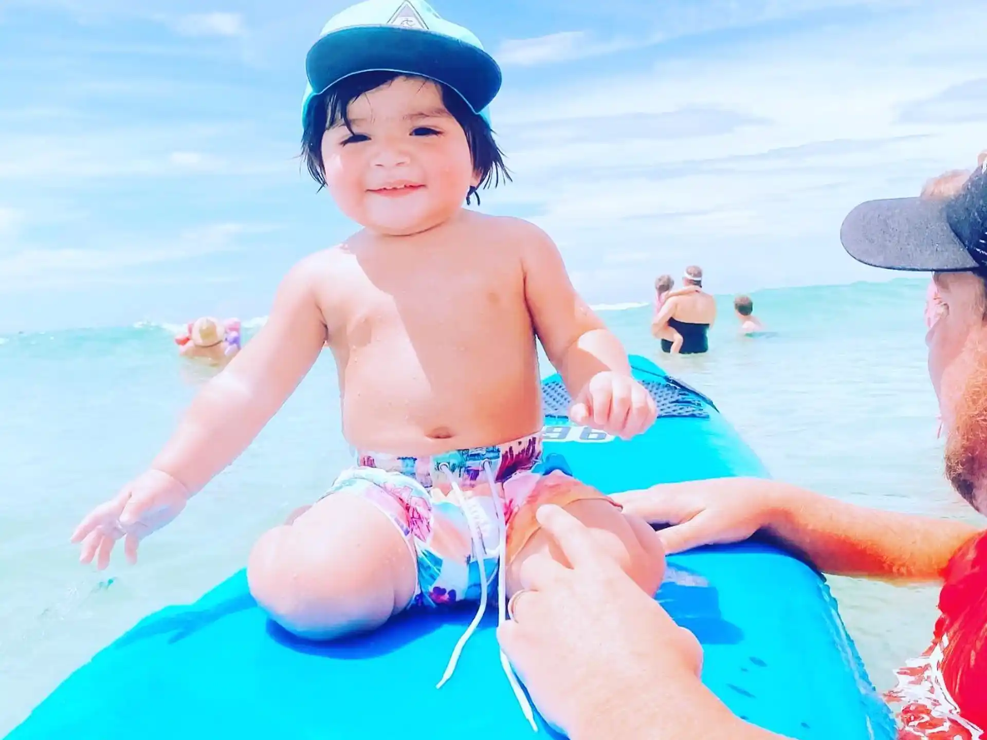 a baby sitting on a man's lap in a pool