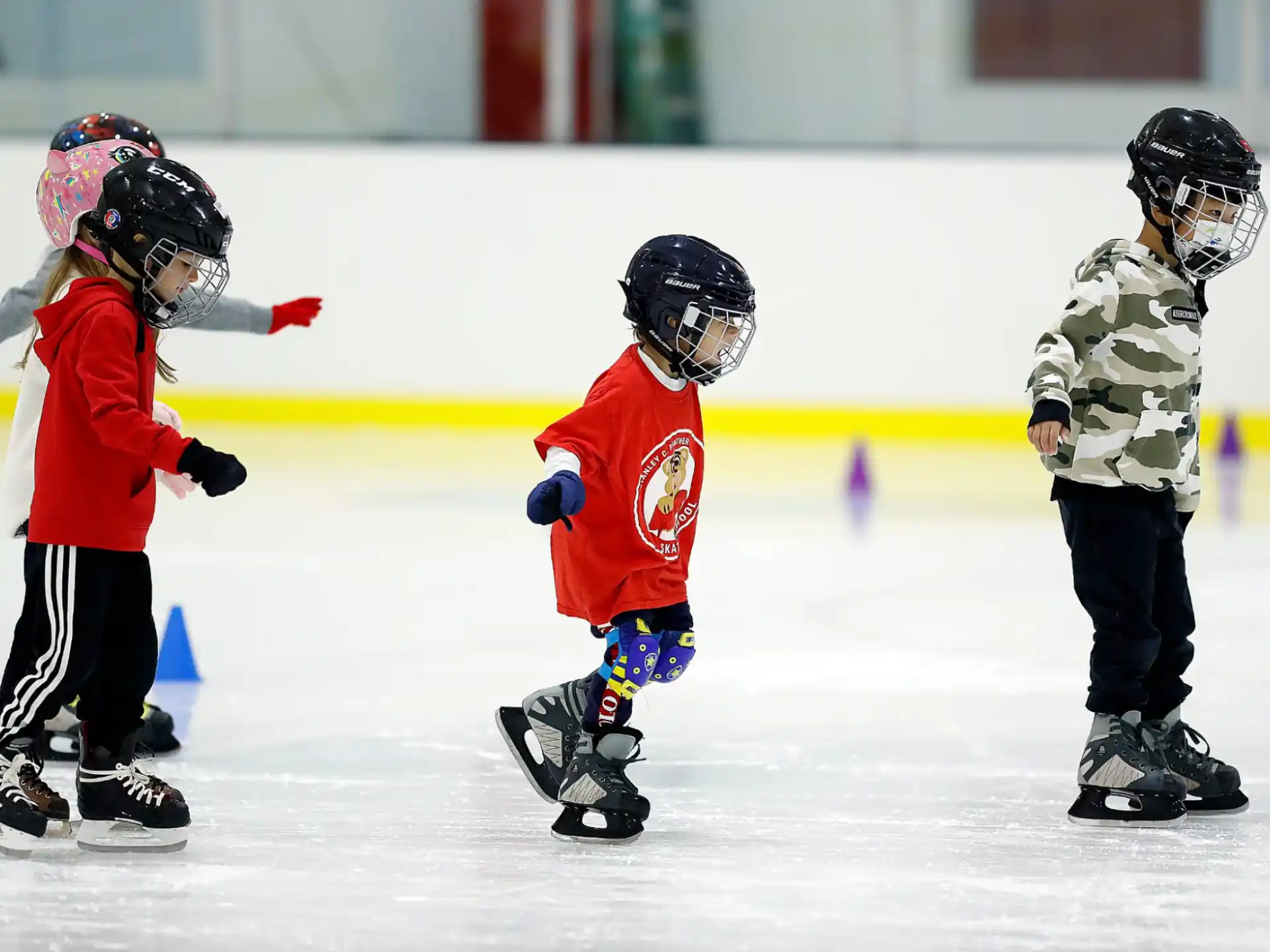 kids wearing helmets and ice skates