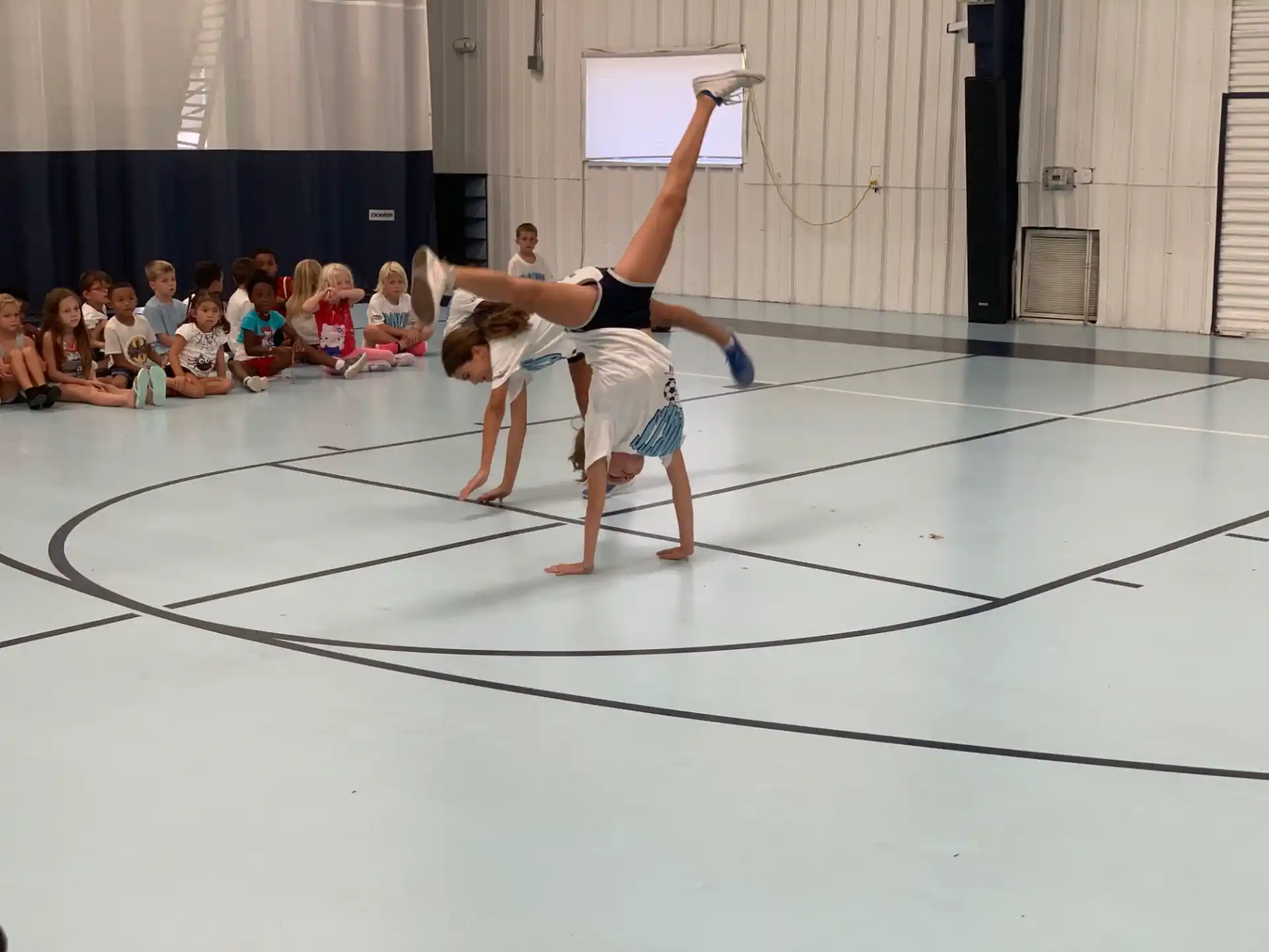 a girl doing a handstand on a mat in front of a crowd