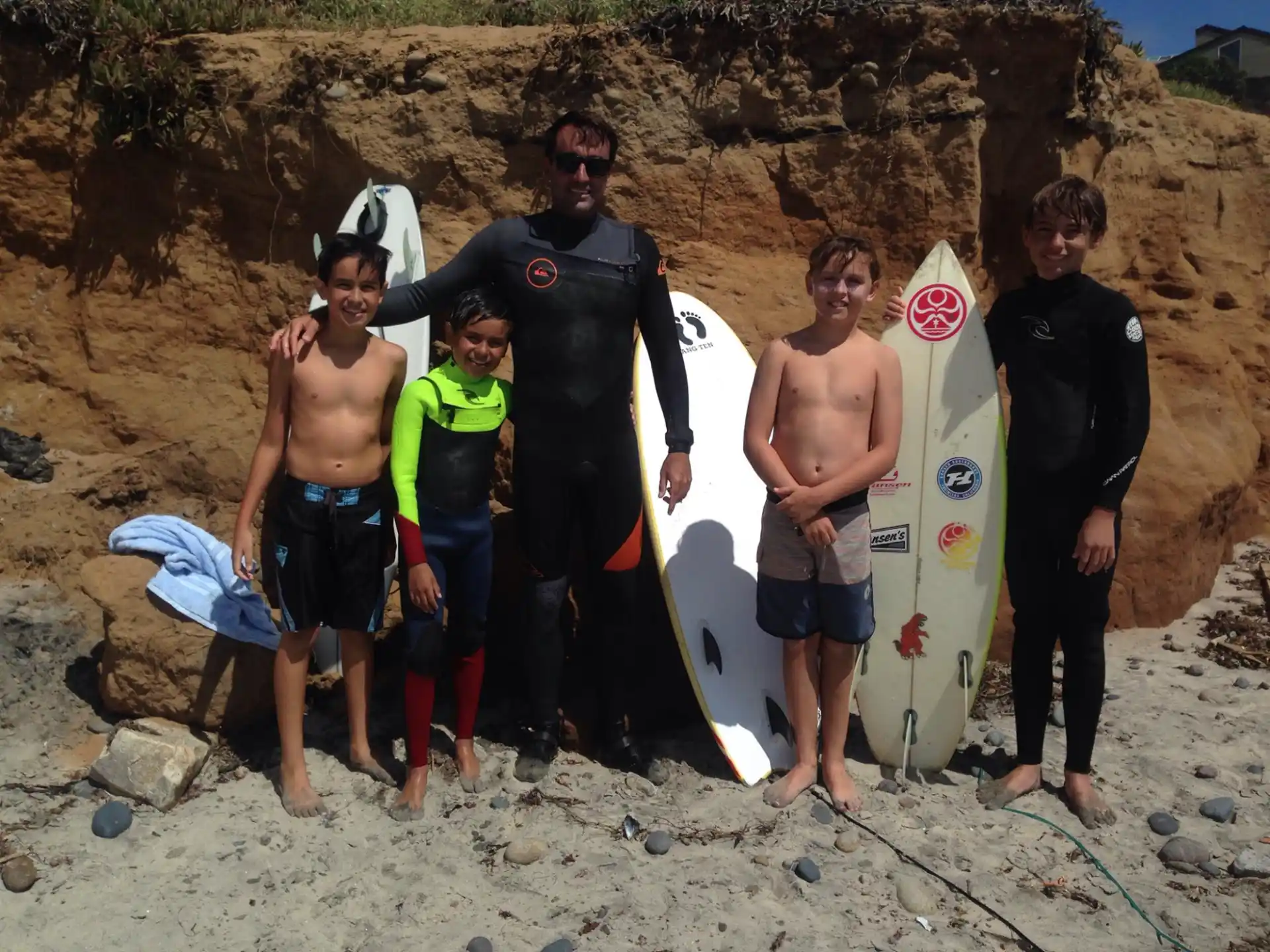 a group of surfers pose with their boards