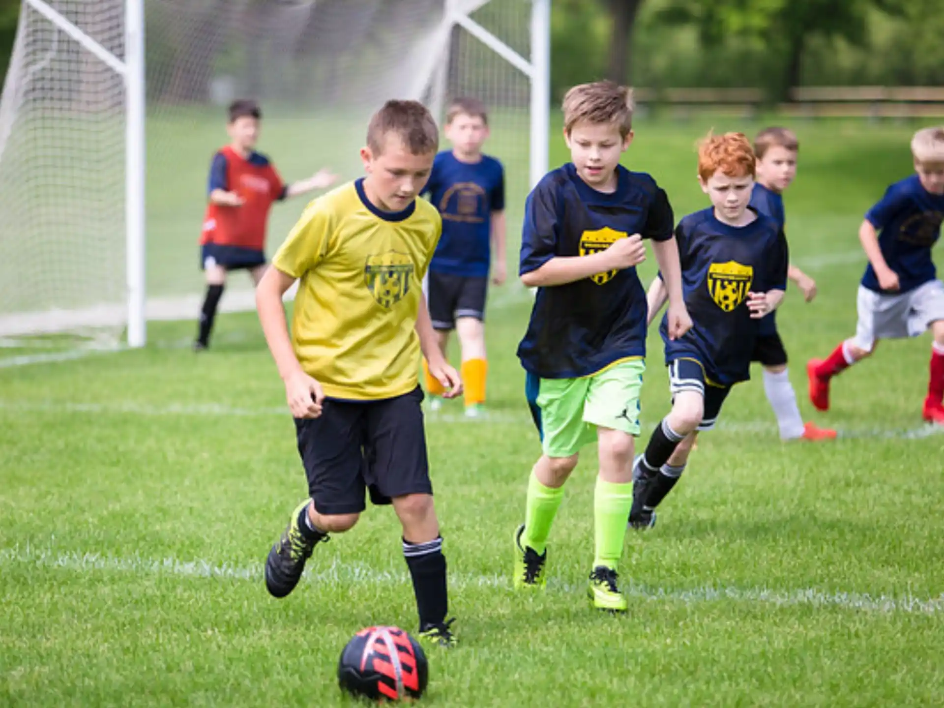 a group of kids compete over a football ball
