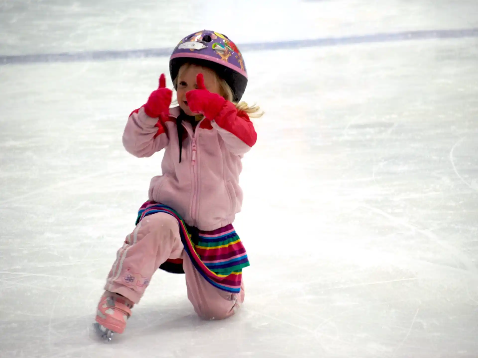 a child wearing a helmet and ice skates