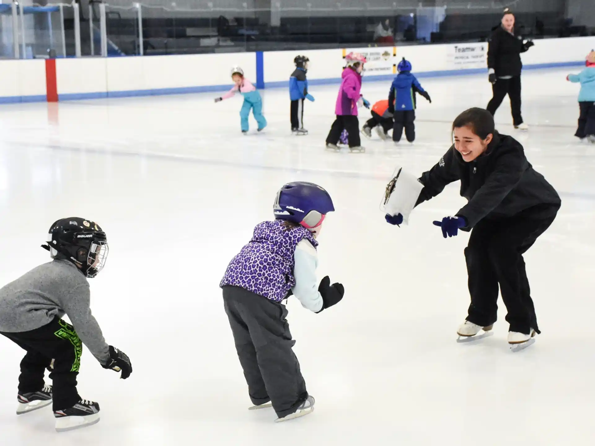 a person and a couple of kids on an ice rink with an audience