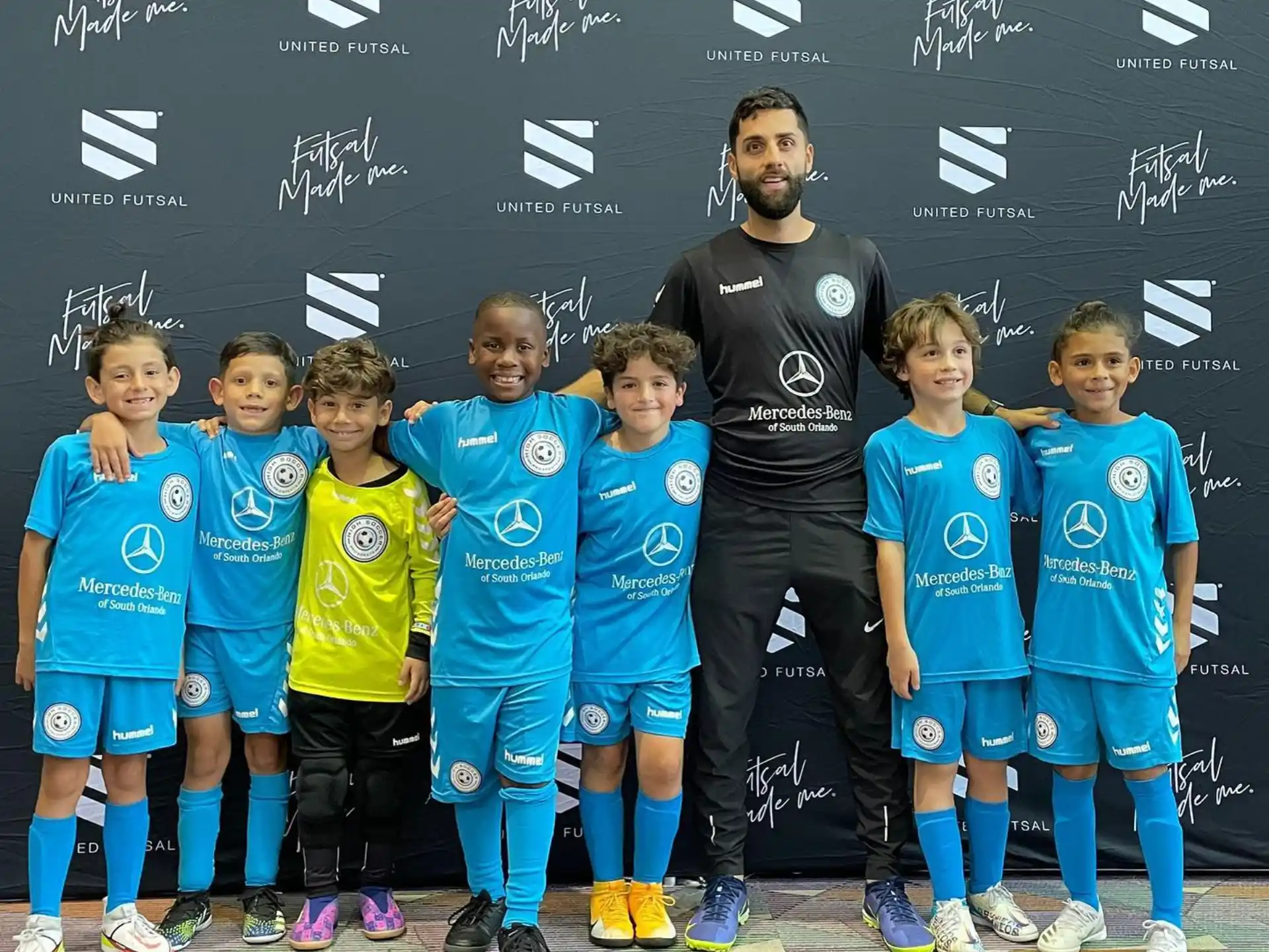 a person standing with a group of kids in front of a blackboard