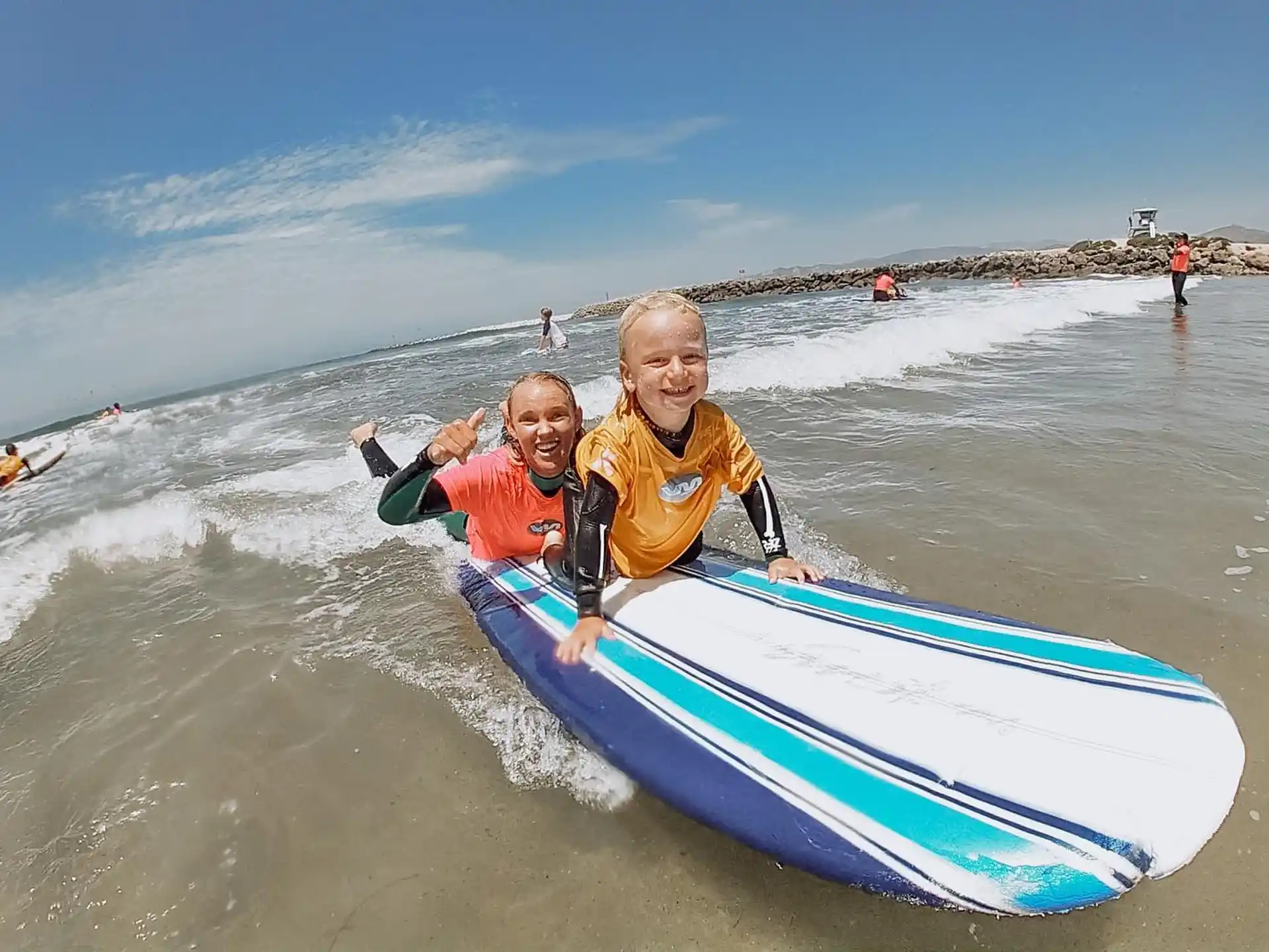 a couple of people ride a surfboard