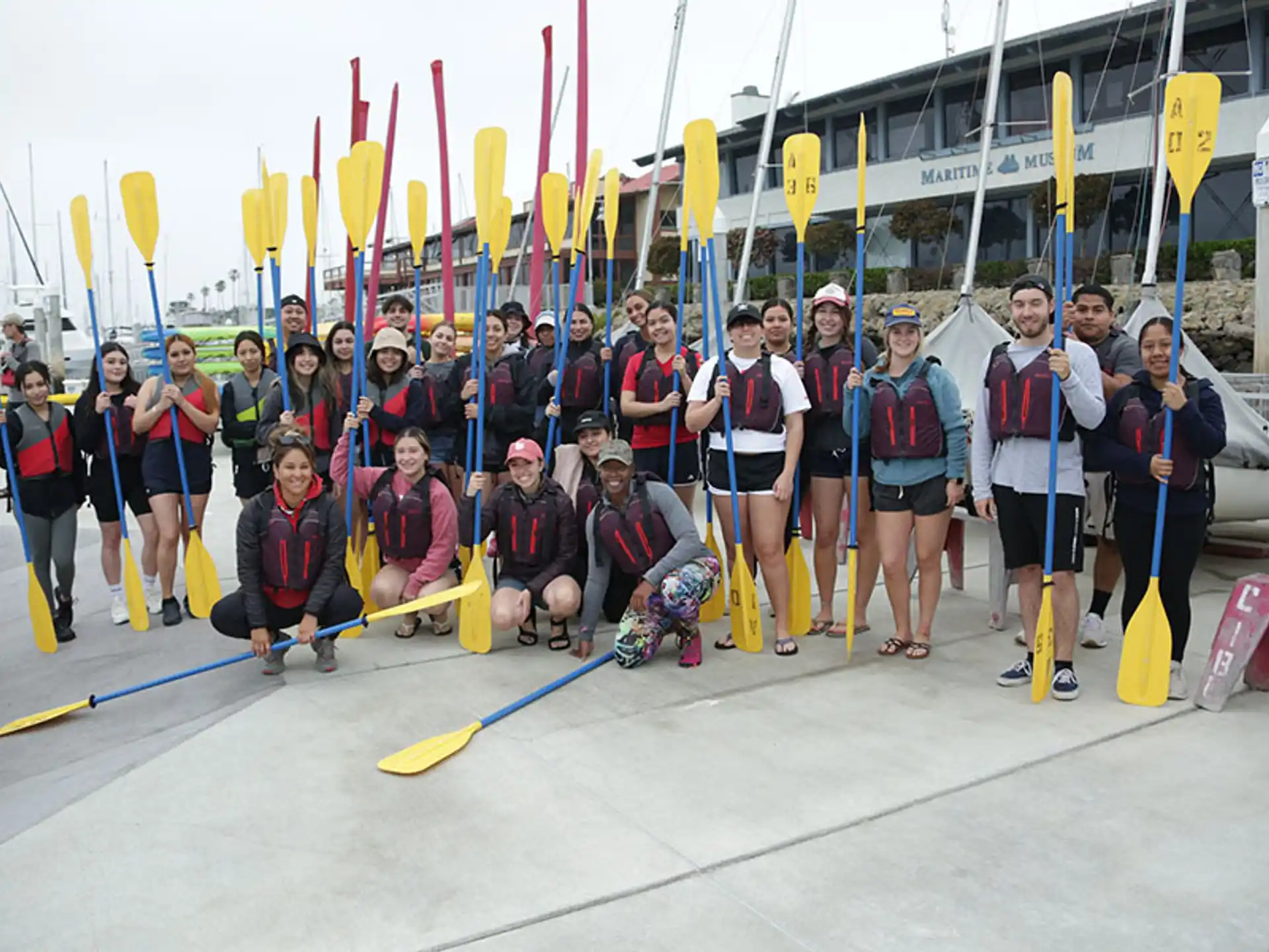 a group of people posing for a photo with a boat in the background