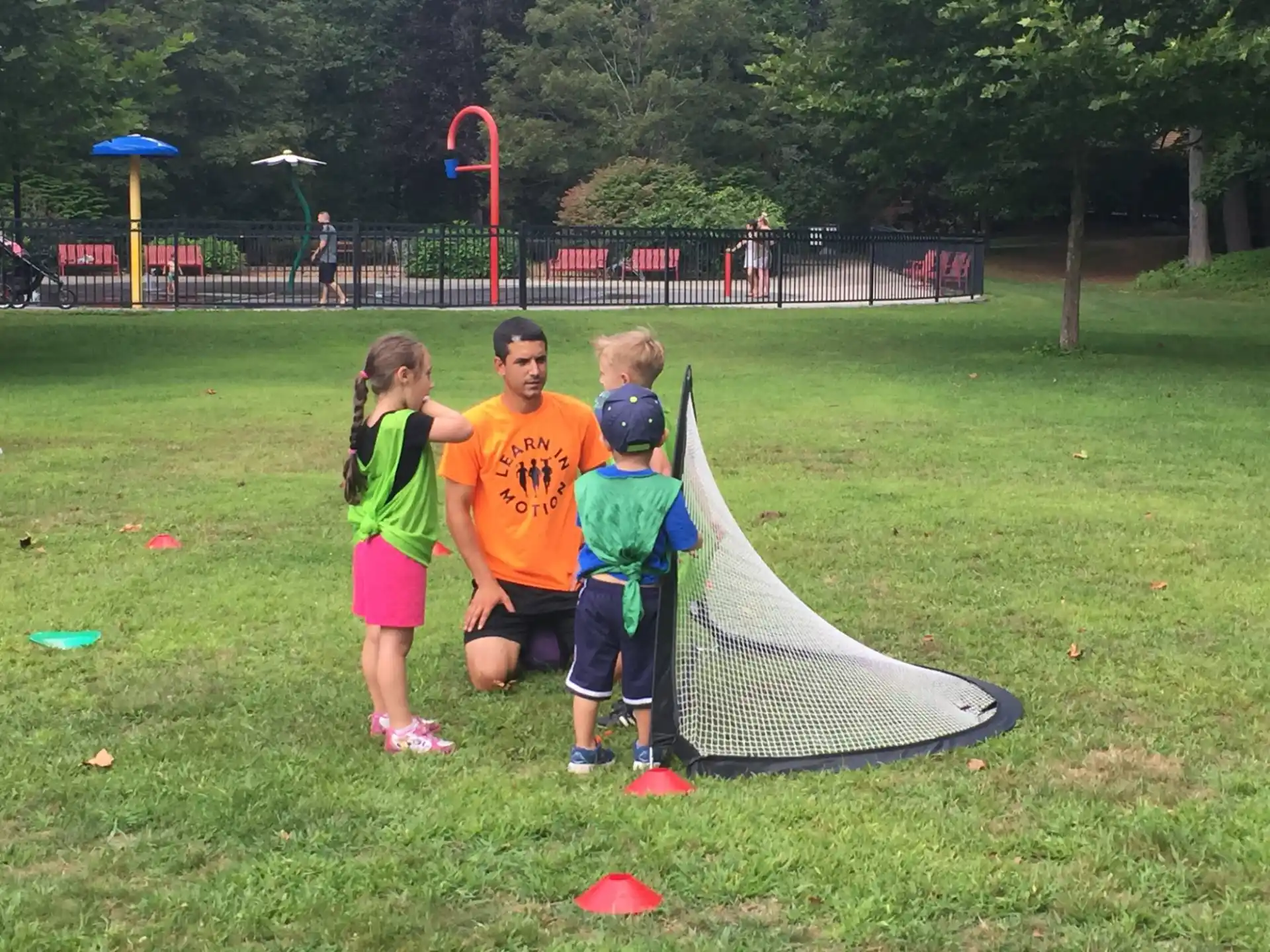 a group of kids playing with a kite in a park