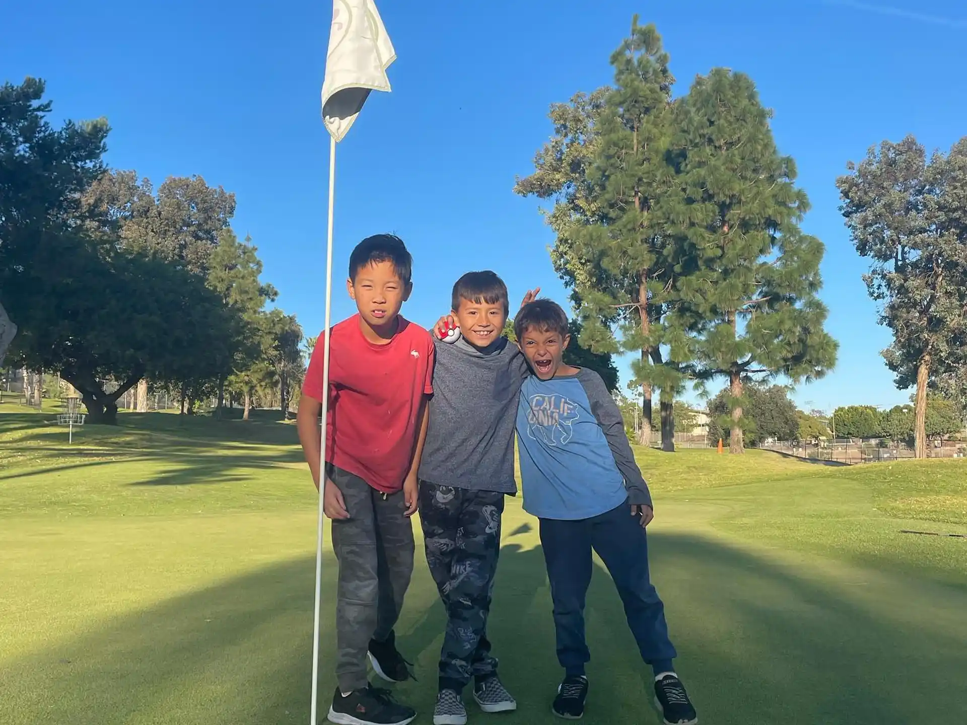 a group of boys standing on a golf course with a flag