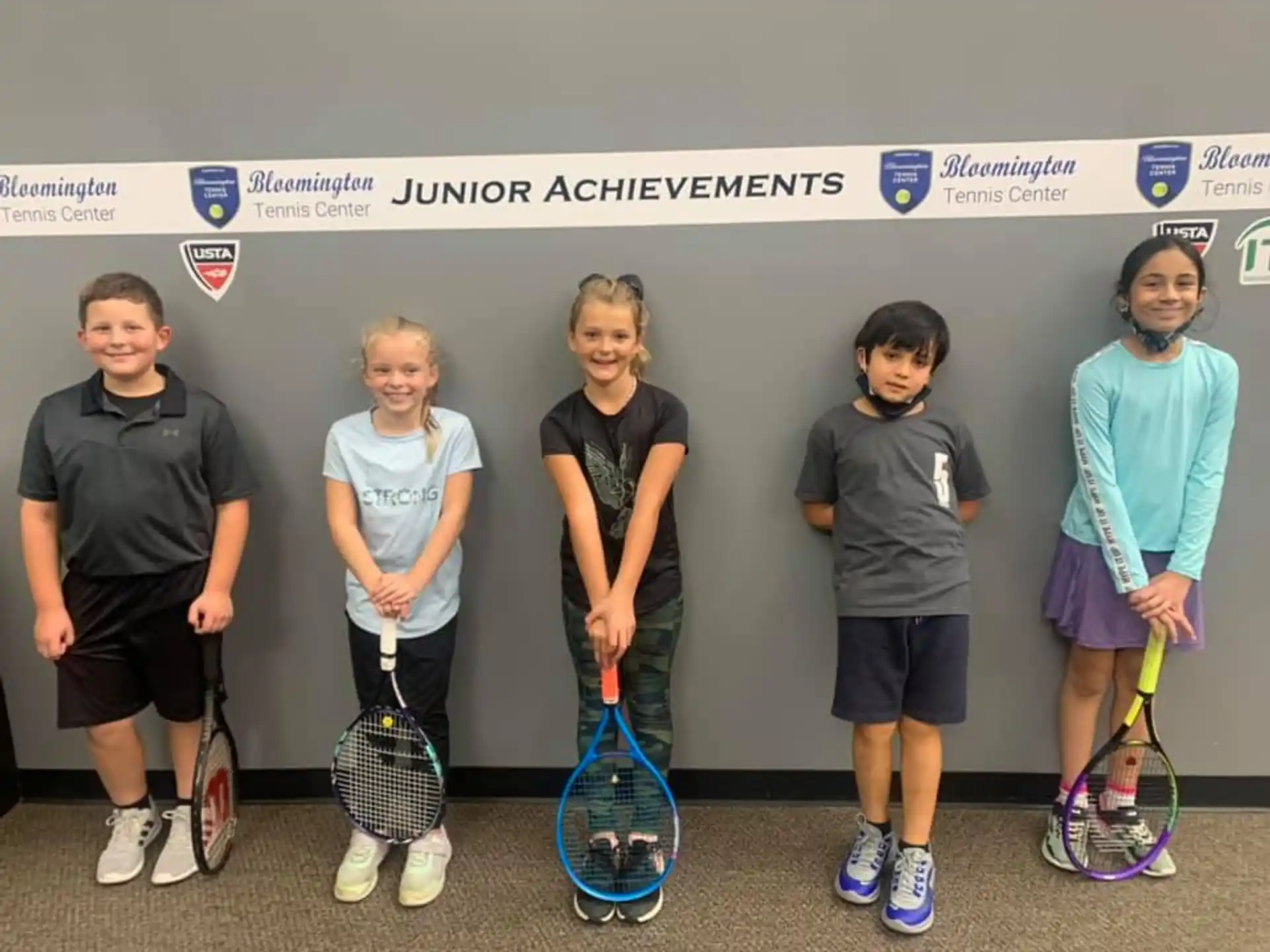 a group of kids holding tennis rackets