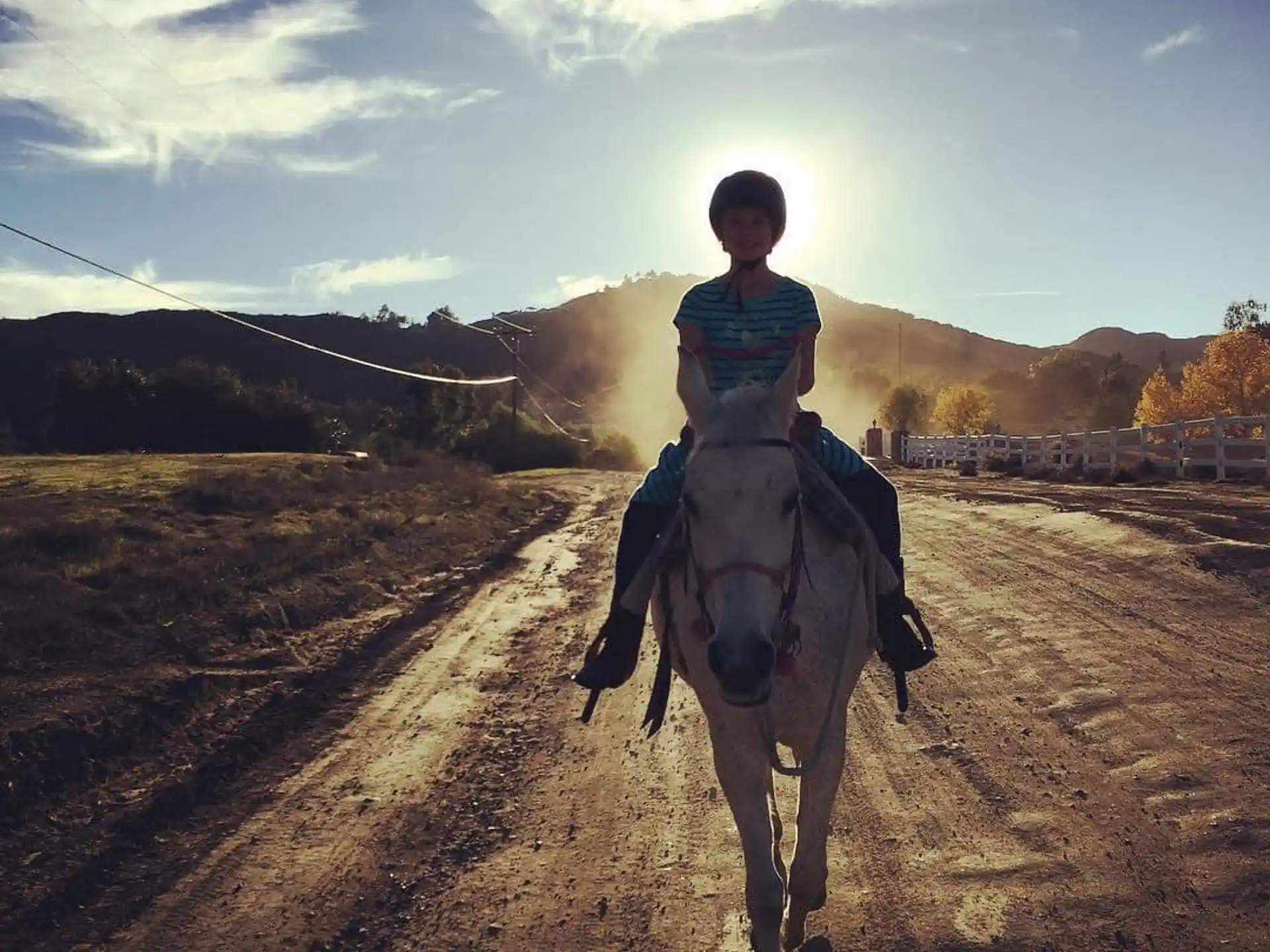 a person riding a horse on a dirt road