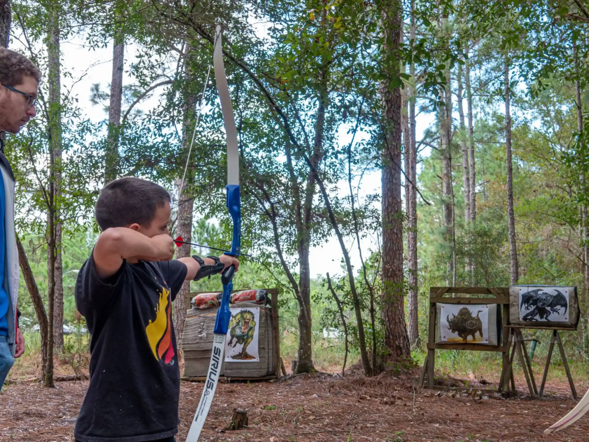 a man and a boy holding a blue and black object in a forest