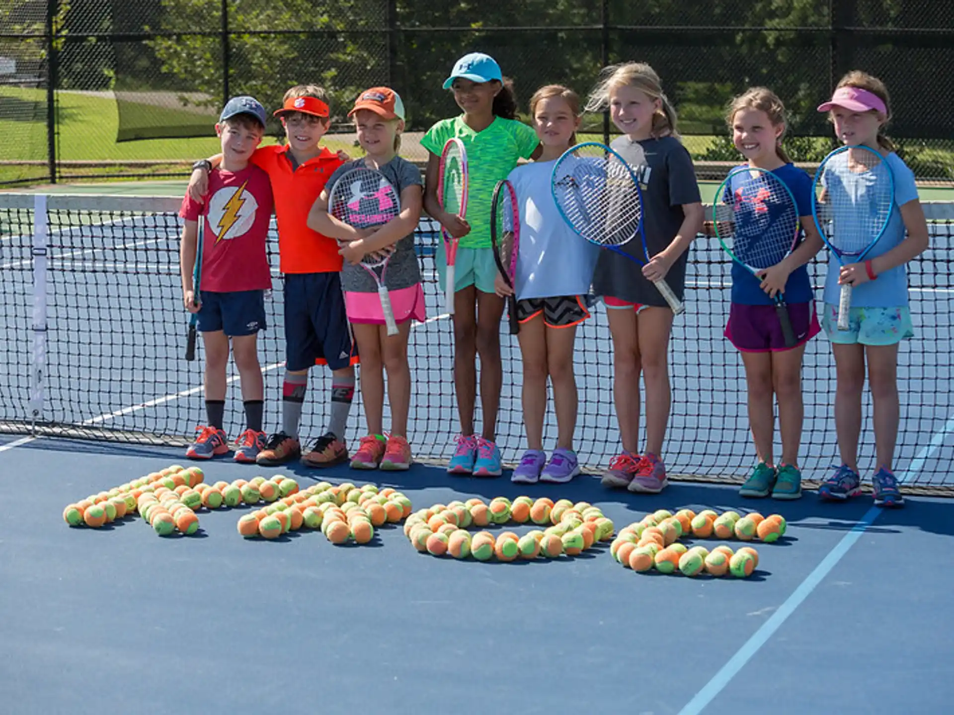 a group of kids holding tennis rackets
