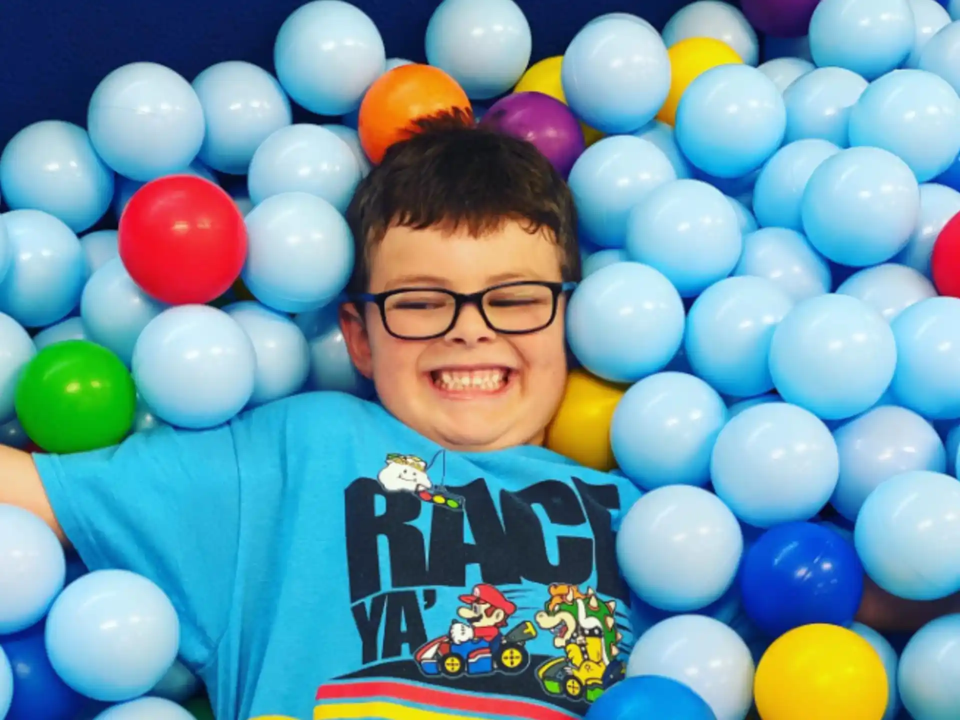 a boy smiling with a bunch of balloons around him